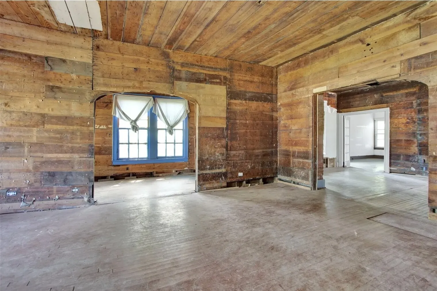 Unfurnished living room featuring wooden ceiling and wood walls