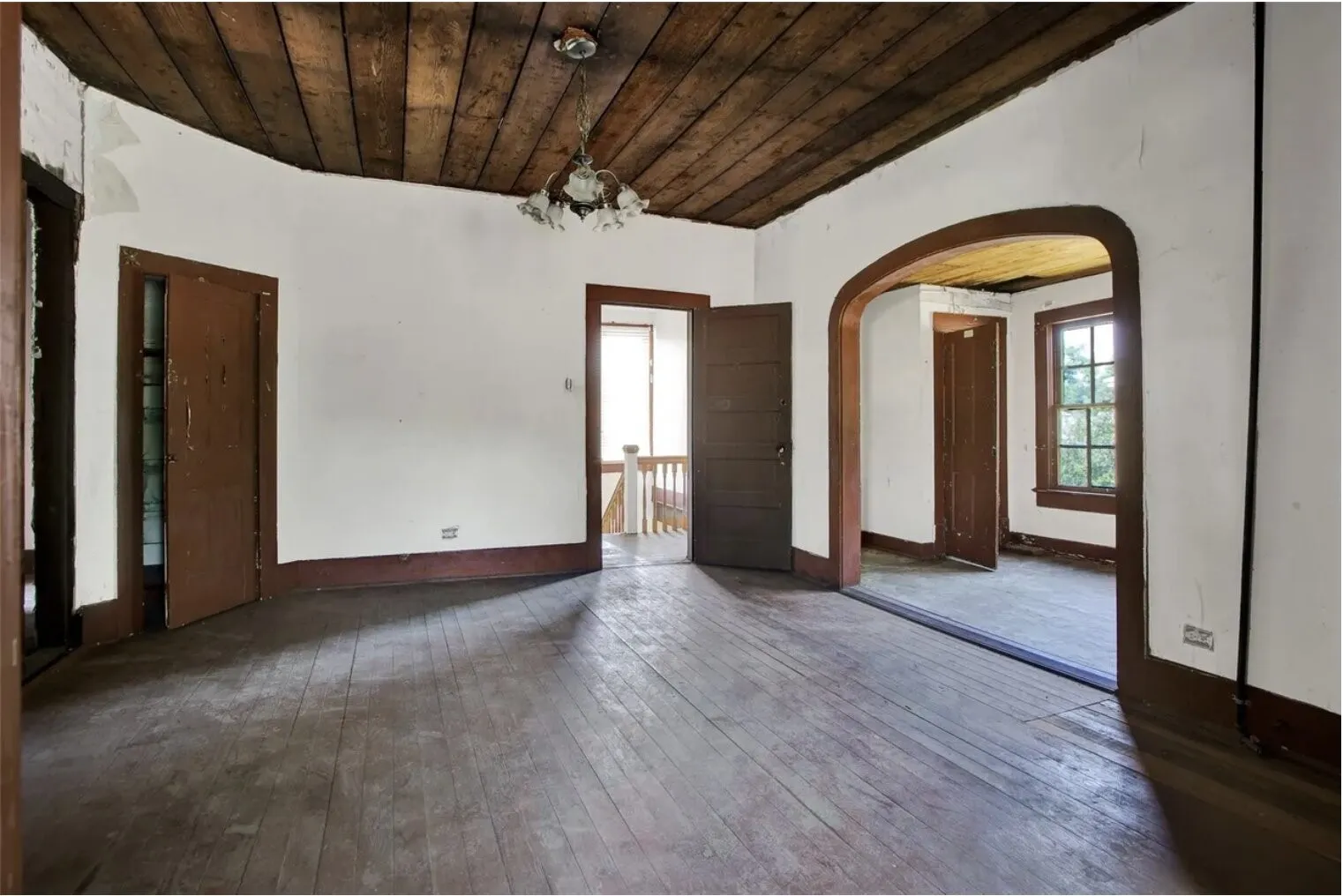 Unfurnished room featuring arched walkways, wood ceiling, hanging lights, and wood-type flooring