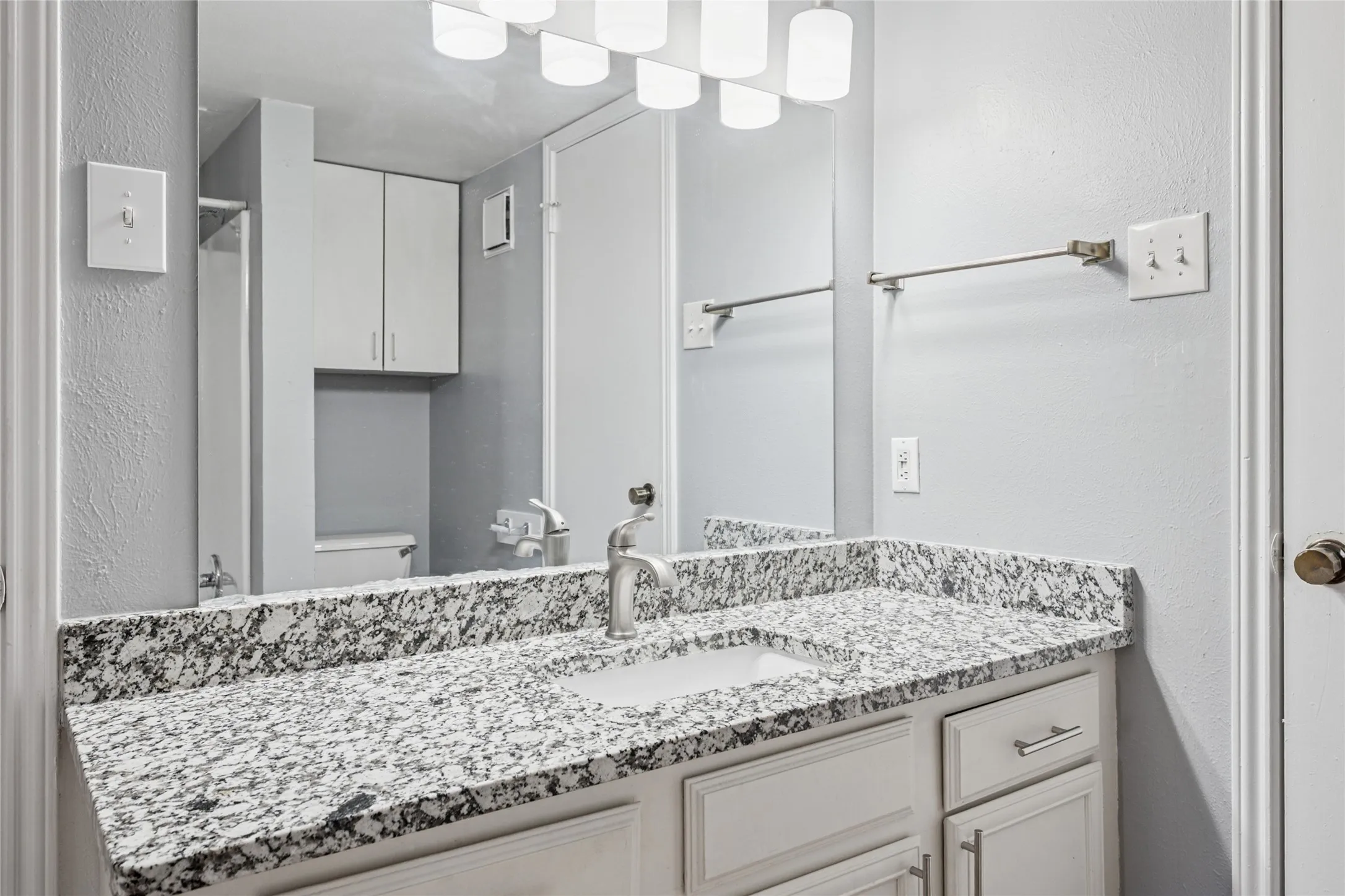 Bathroom with granite counters and custom light