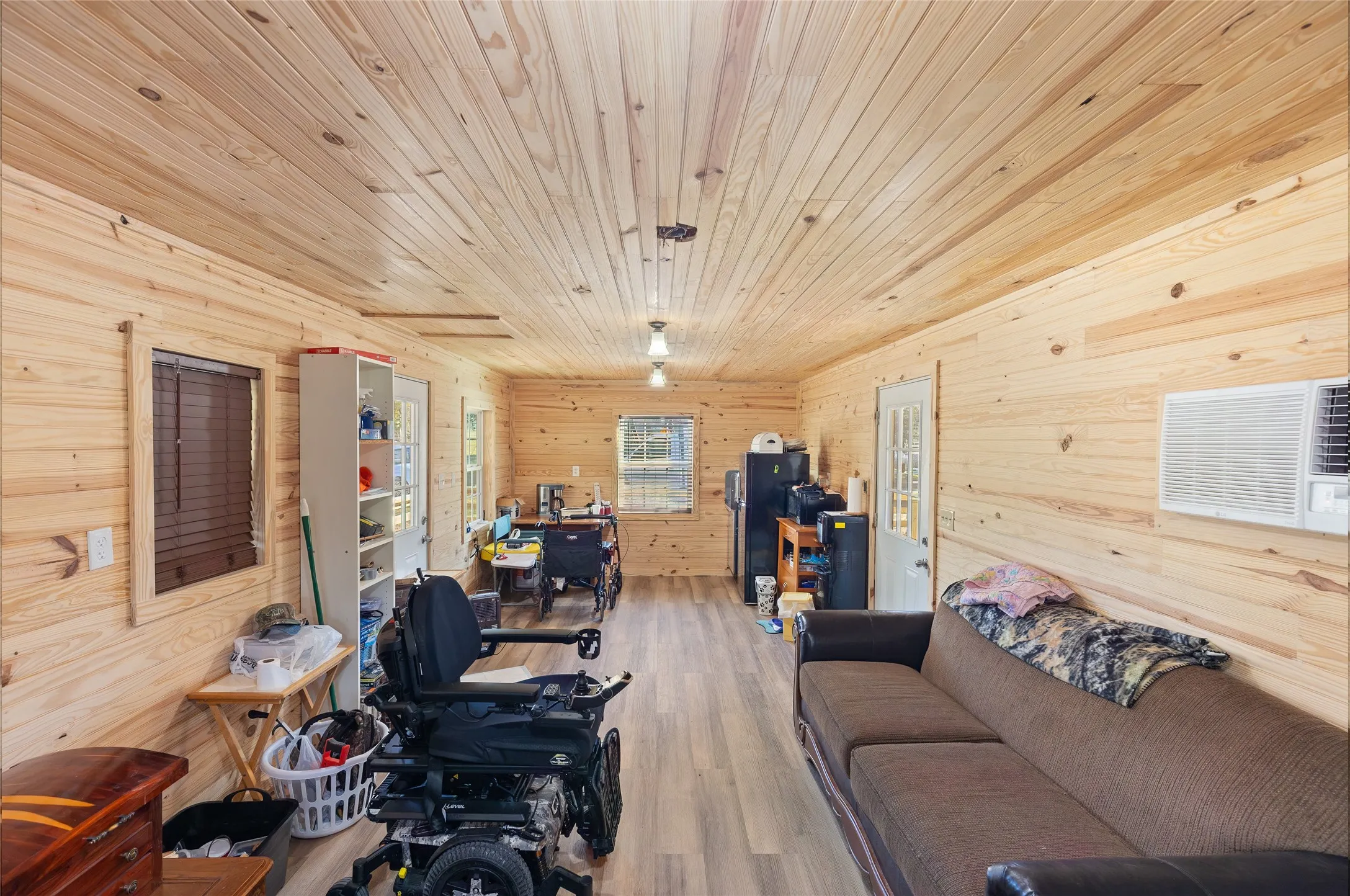 Living room featuring wood walls, light wood finished floors, and wood ceiling