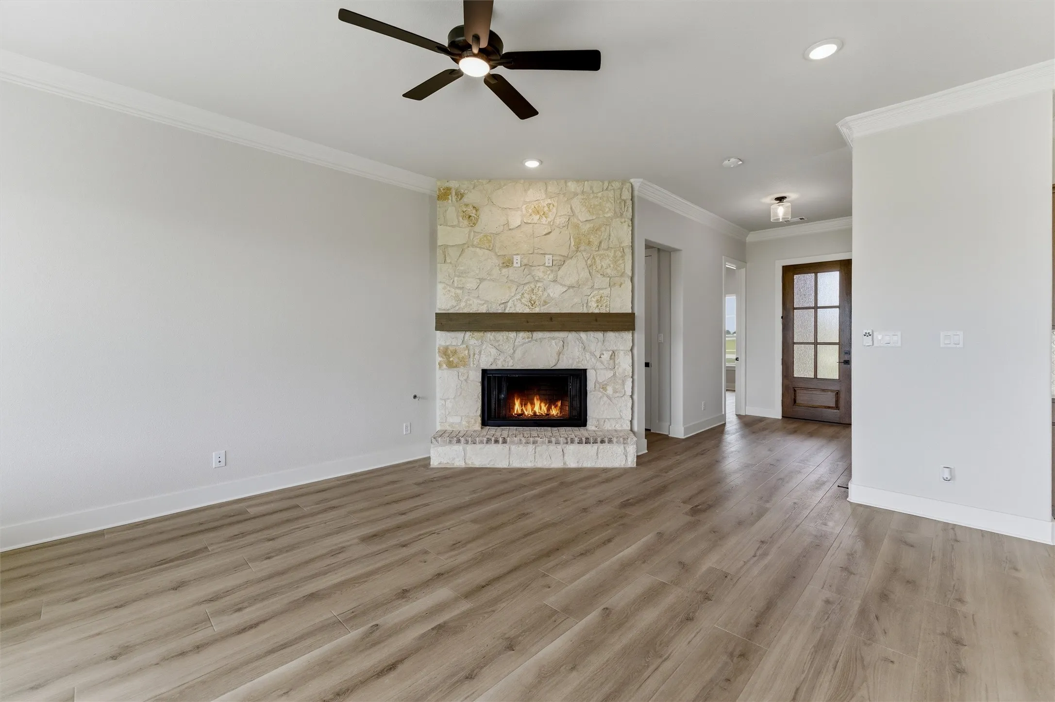 Living area featuring a stone fireplace with a wood mantel, wood-finish flooring, recessed lighting, and a ceiling fan