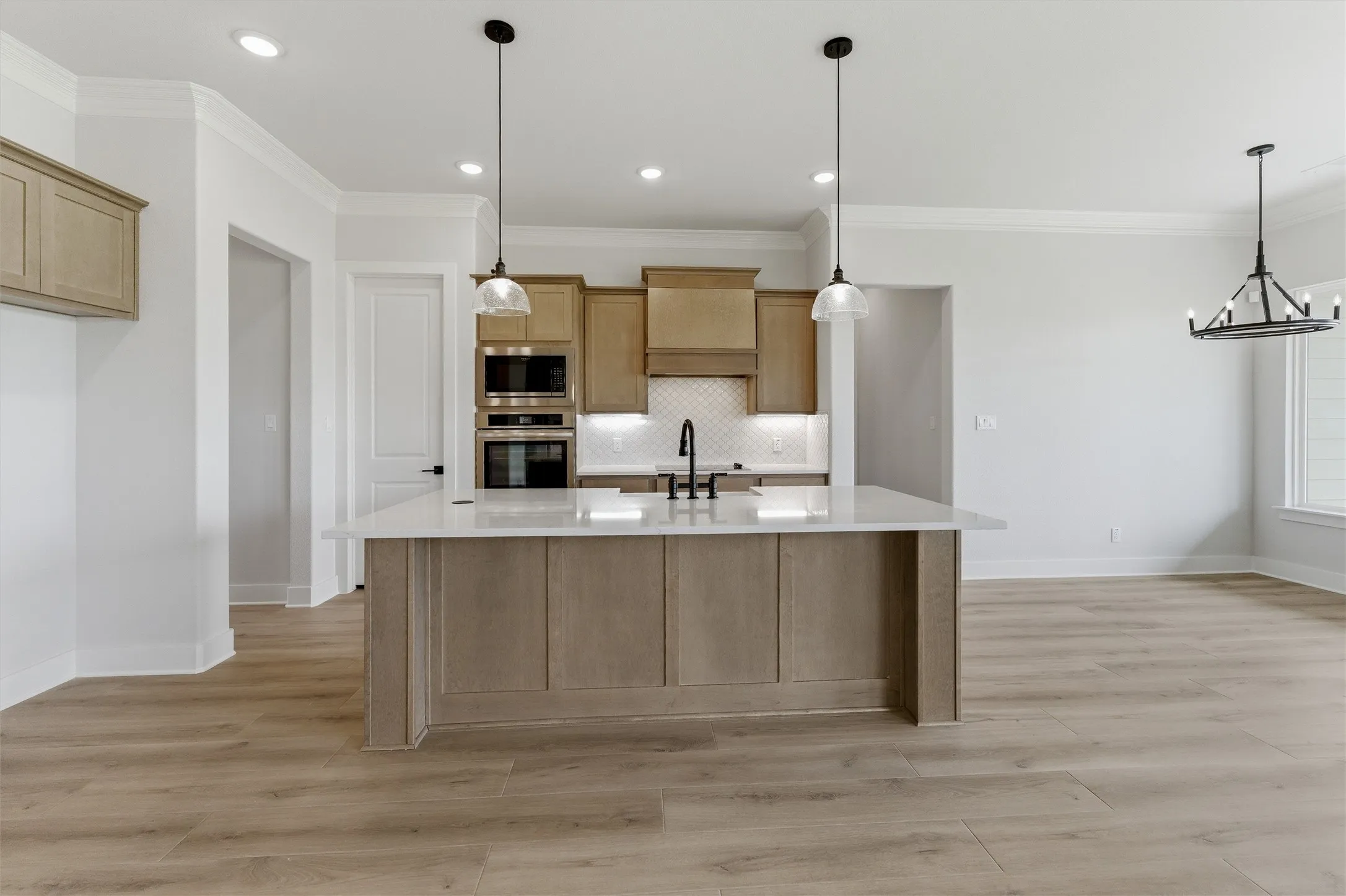 Kitchen featuring a large central island with a light-toned countertop, wood-finish flooring, recessed lighting, and pendant fixtures