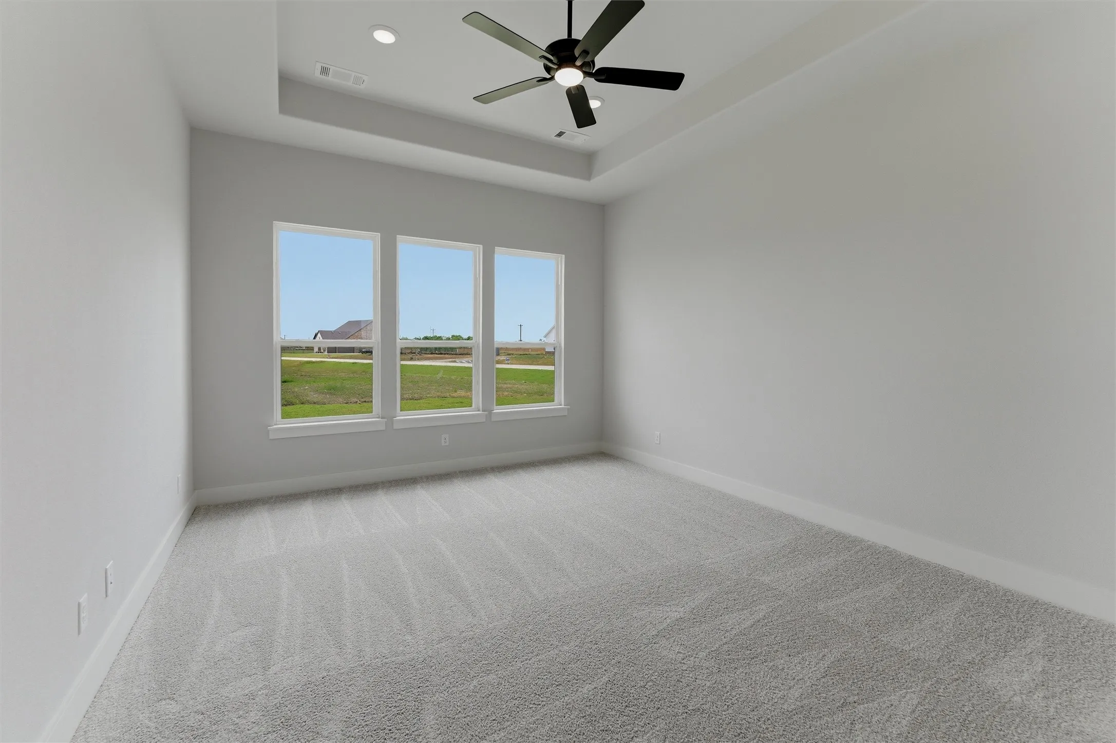 Spacious room featuring a tray ceiling with recessed lighting and a ceiling fan