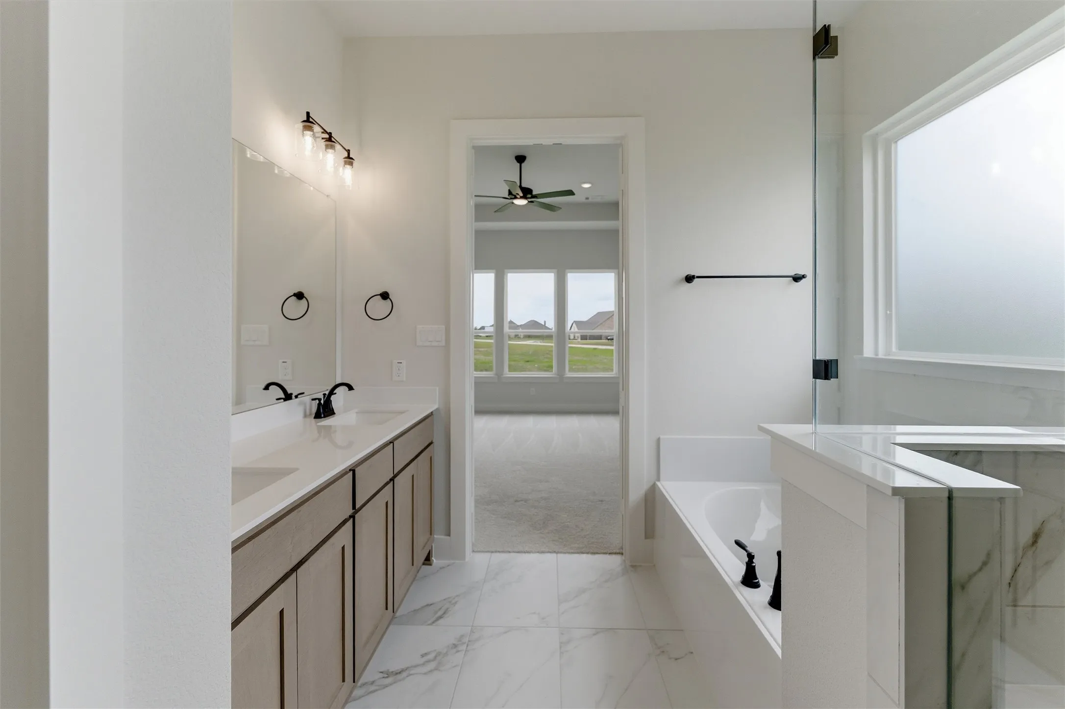 Spacious bathroom featuring a double vanity with stone countertops, undermount sinks, and matte black fixtures