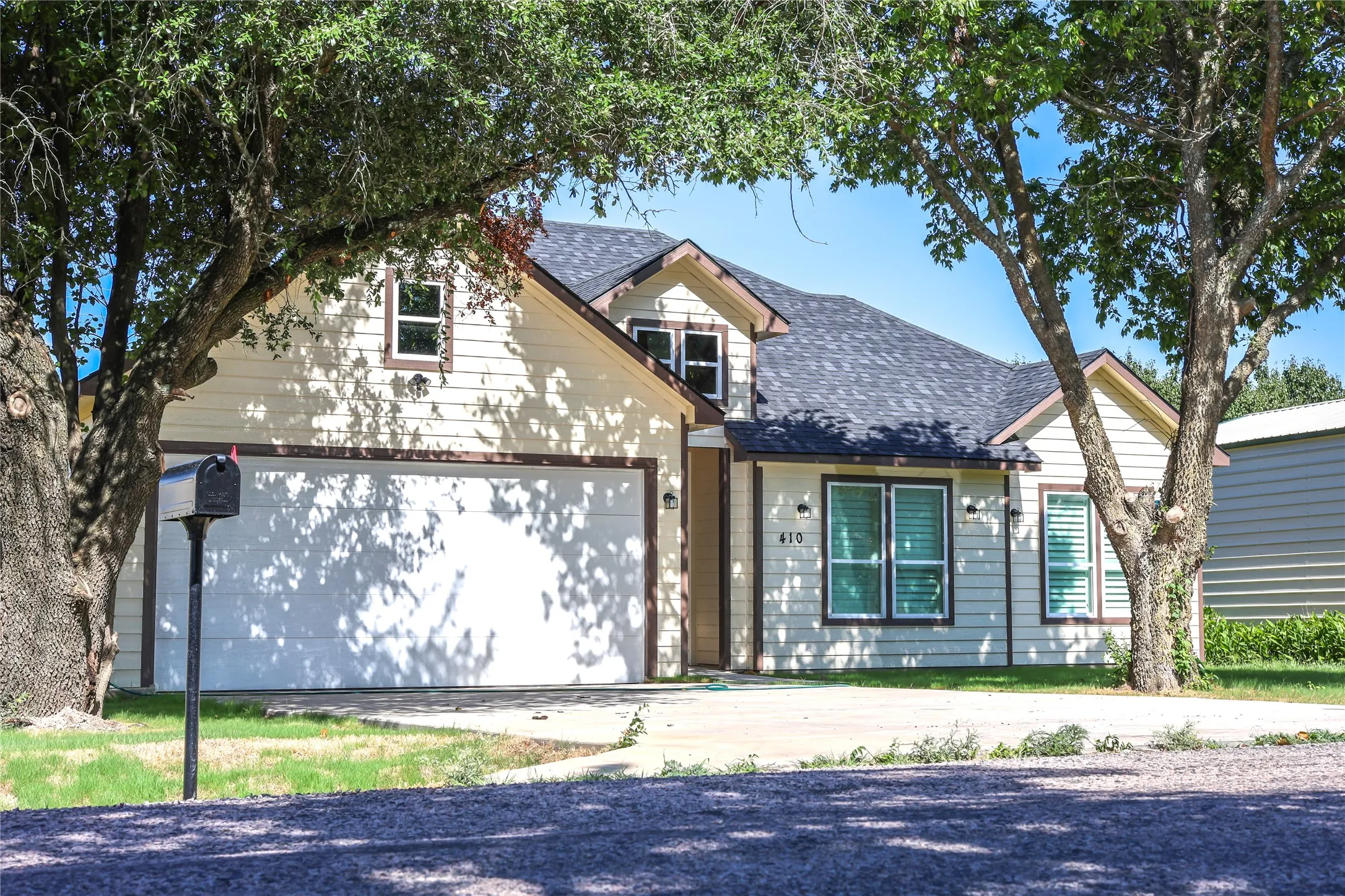 View of front facade with roof with shingles, a garage, and concrete driveway
