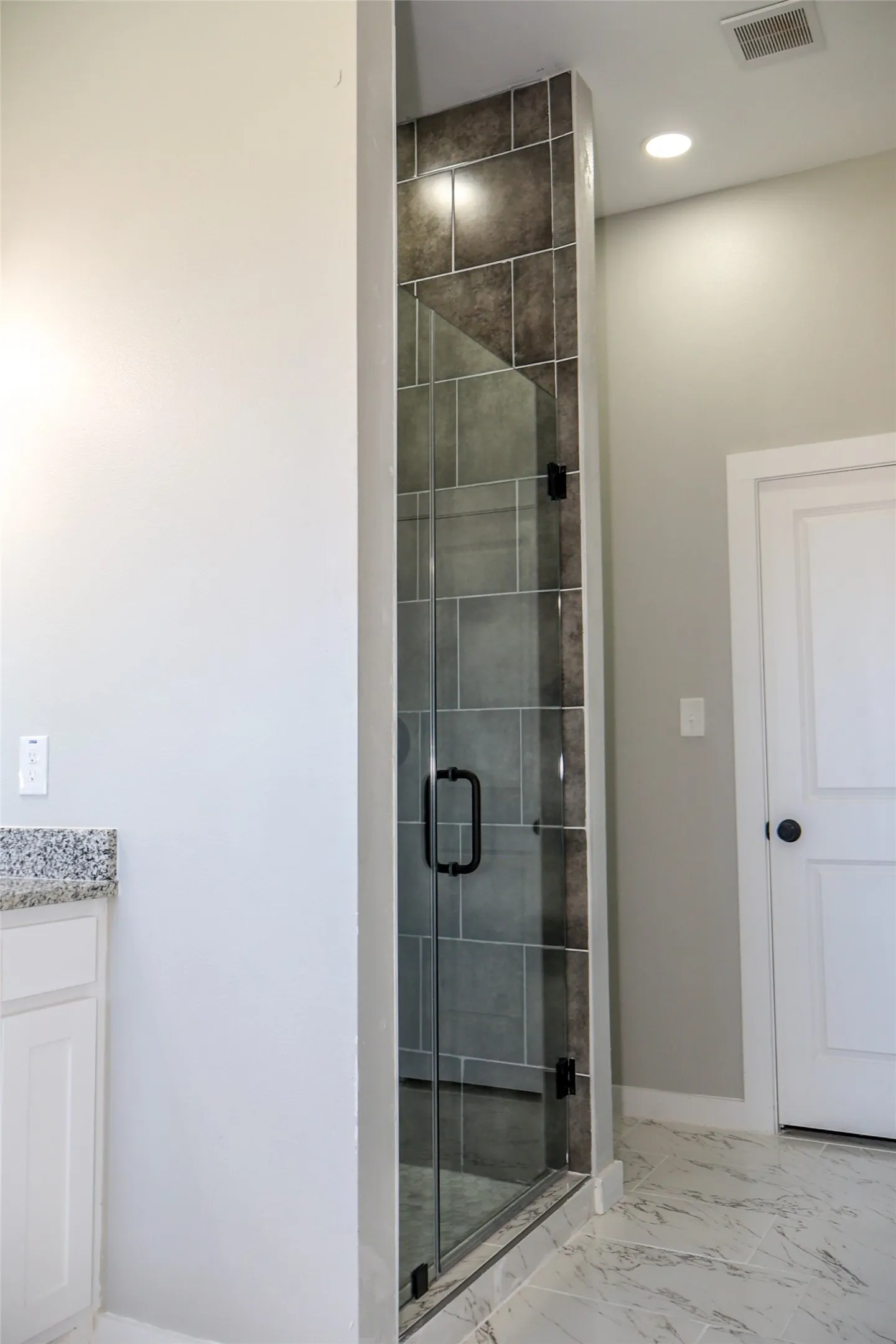Bathroom featuring light marble finish floors, vanity, a shower stall, and recessed lighting