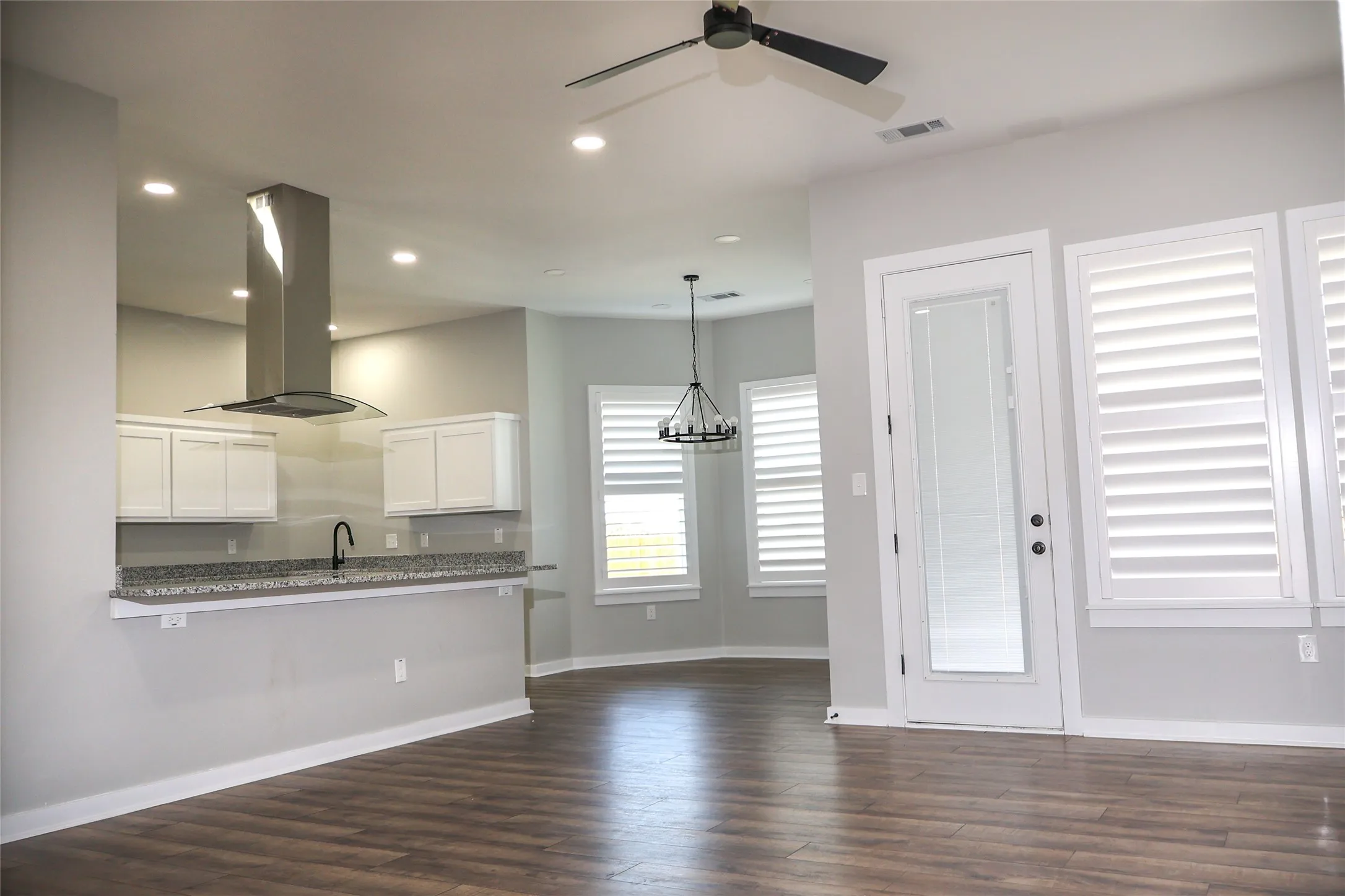 Kitchen featuring white cabinetry, island exhaust hood, dark wood-type flooring, a chandelier, and ceiling fan