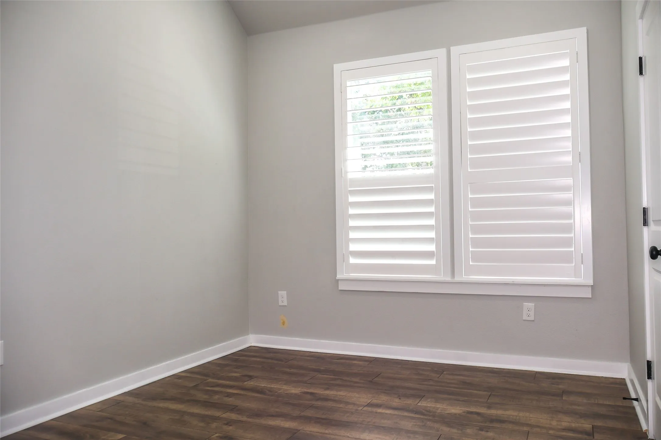 Spare room with dark wood-type flooring and baseboards
