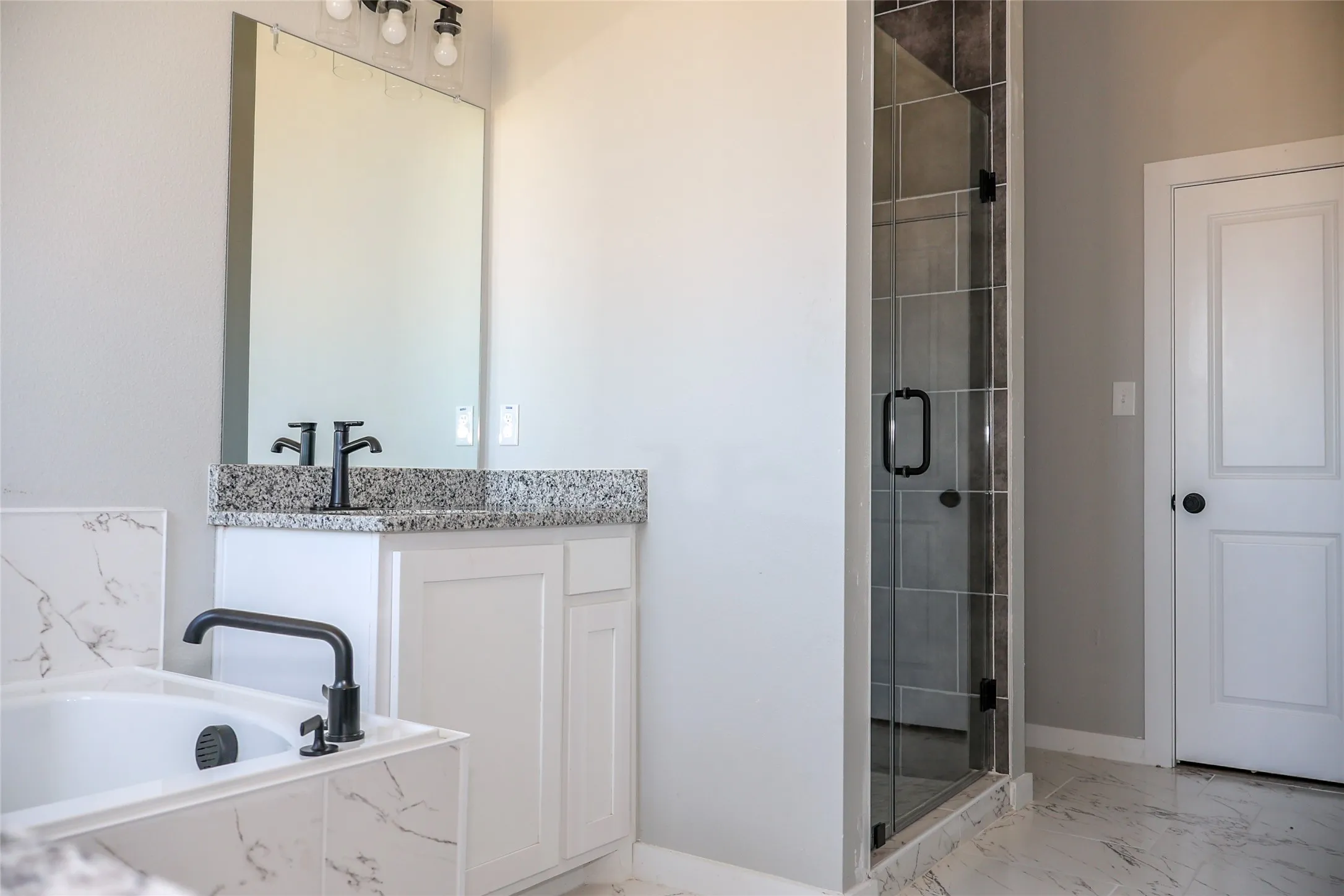 Bathroom with vanity, a shower stall, light marble finish flooring, and a garden tub