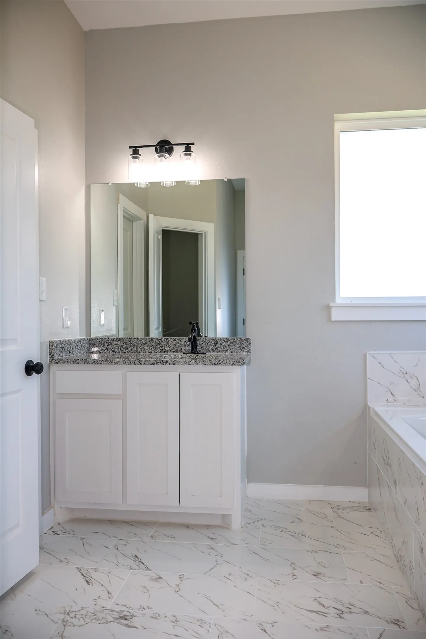 Bathroom with vanity, a garden tub, and light marble finish floors