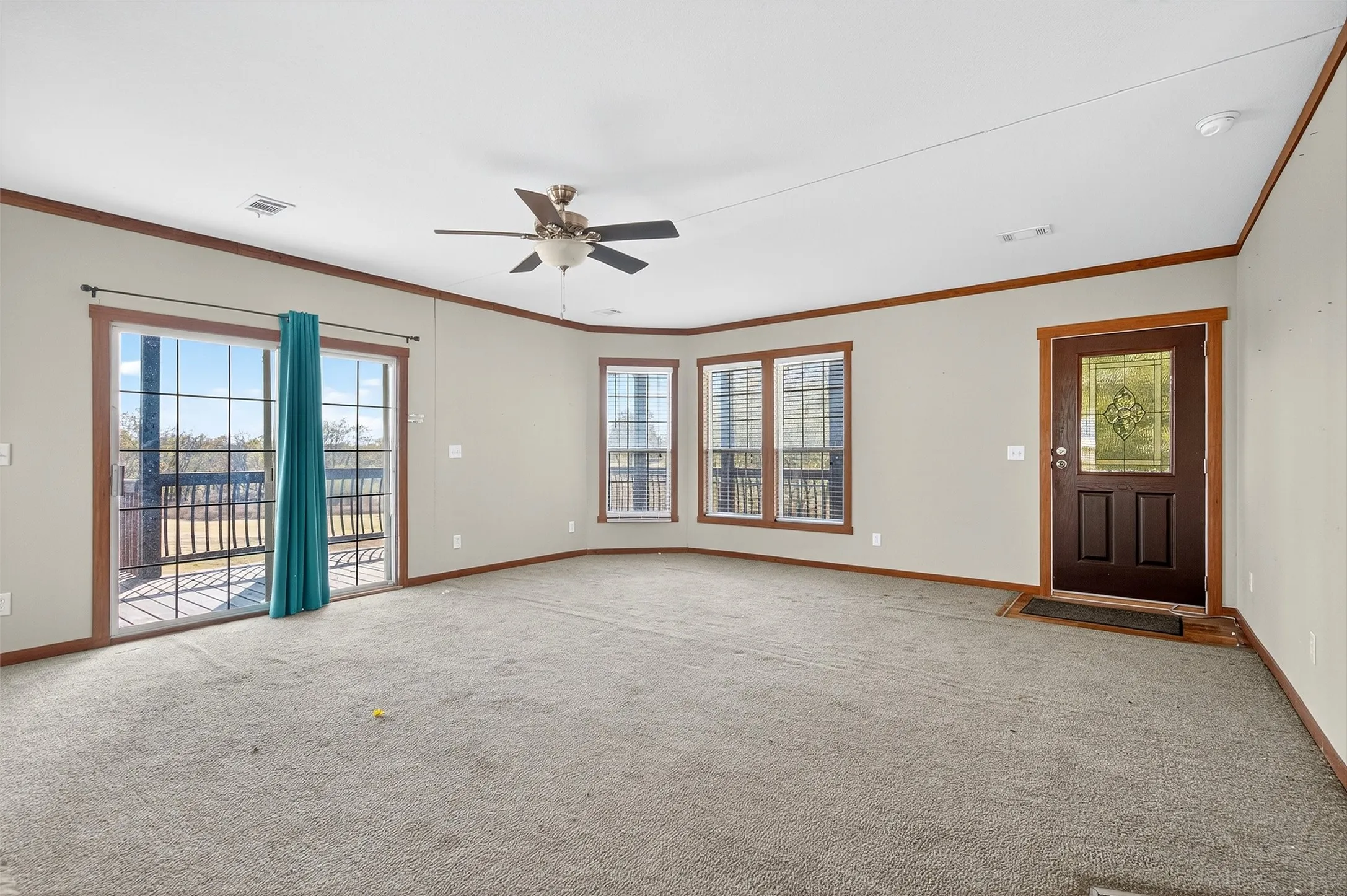 Empty room featuring crown molding, plenty of natural light, carpet, and ceiling fan