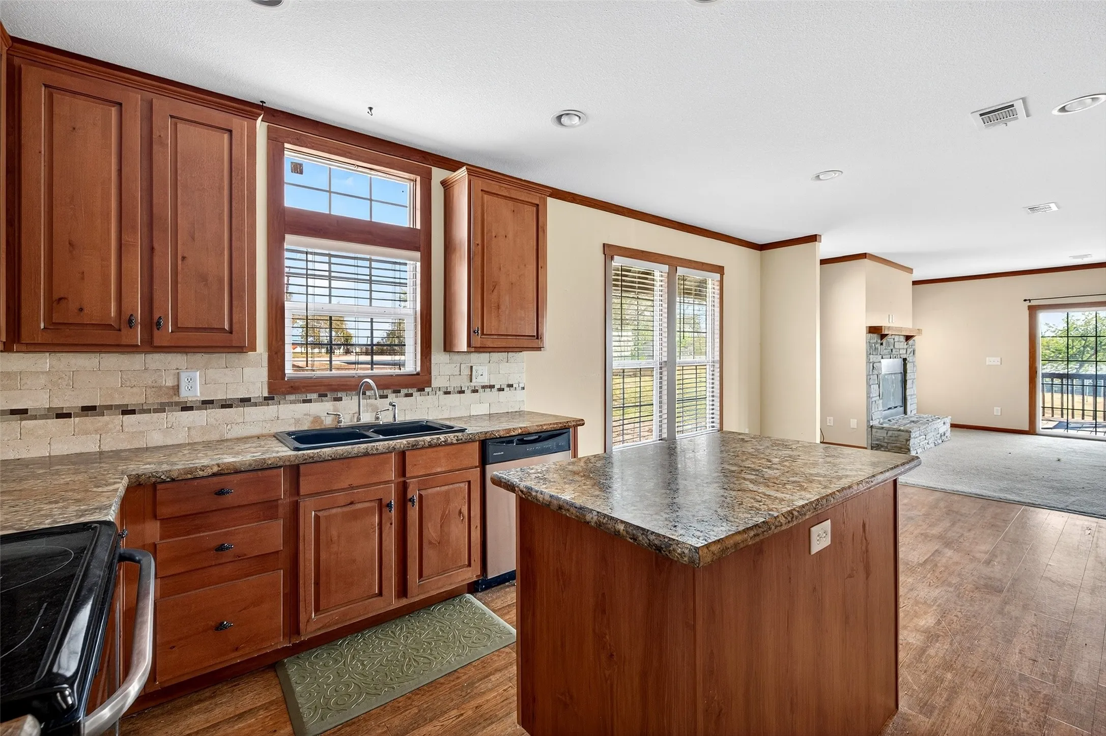 Kitchen with a center island, range with electric stovetop, open floor plan, backsplash, and brown cabinets