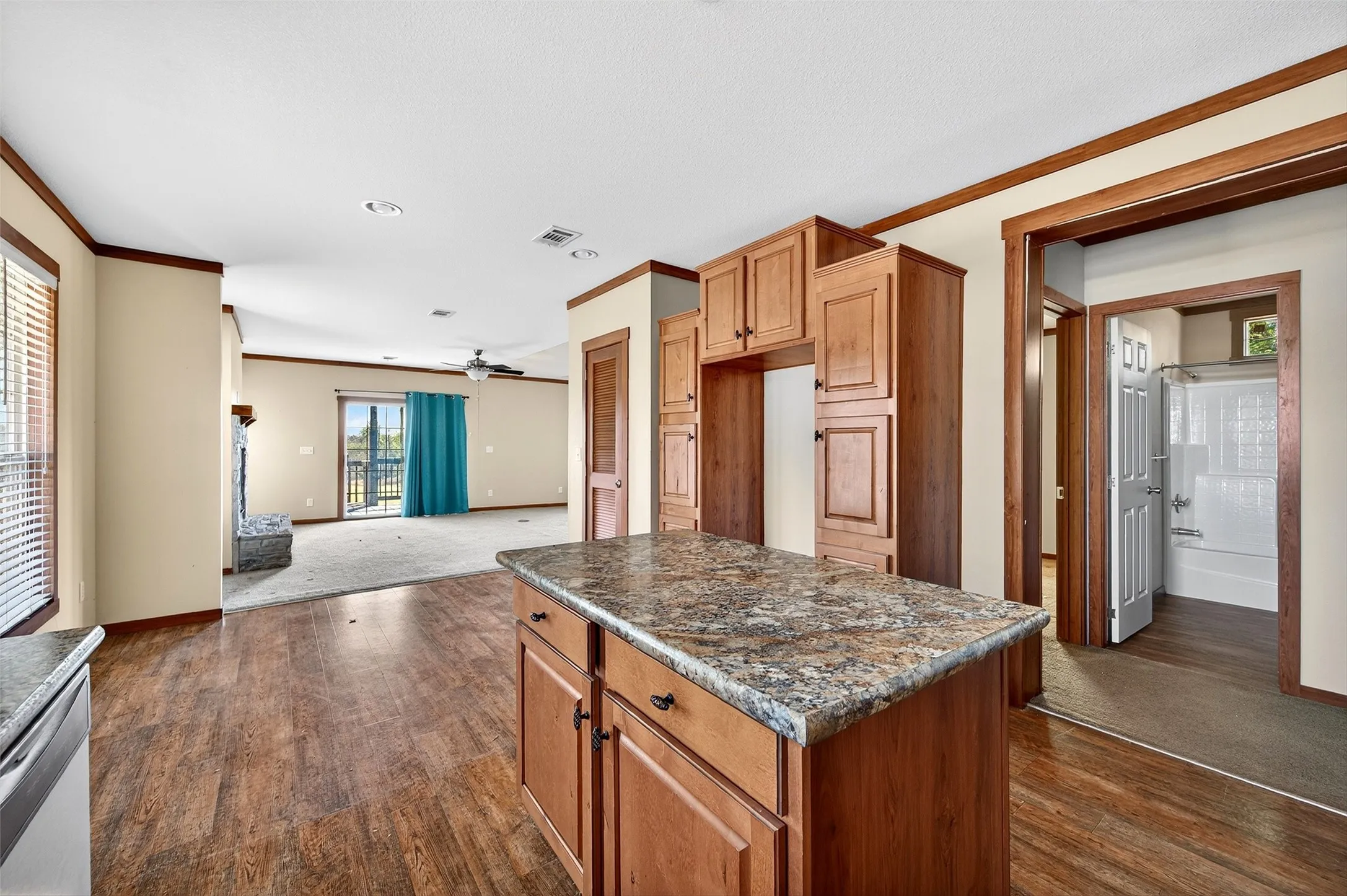 Kitchen with brown cabinetry, ornamental molding, a center island, open floor plan, and ceiling fan