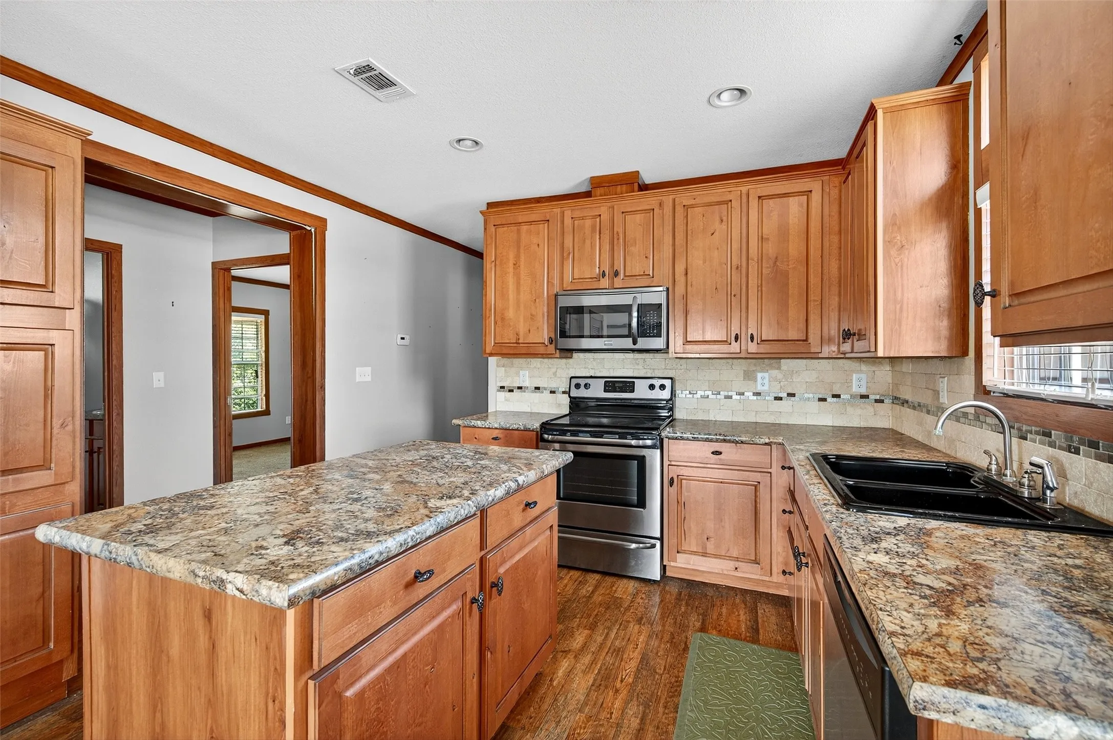 Kitchen with stainless steel appliances, tasteful backsplash, a center island, ornamental molding, and healthy amount of natural light
