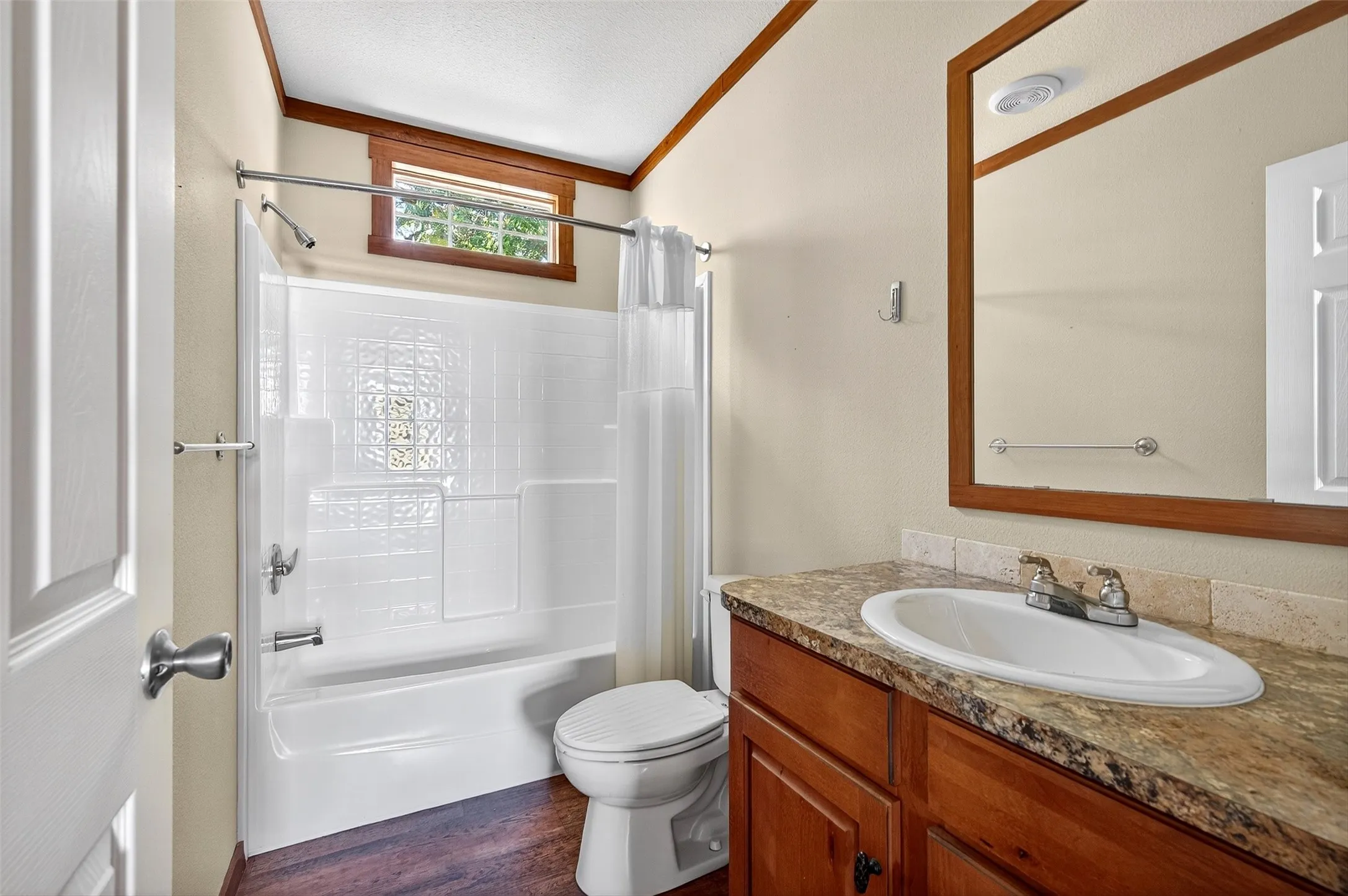 Full bath with shower / bathtub combination with curtain, vanity, dark wood-style floors, ornamental molding, and a textured ceiling