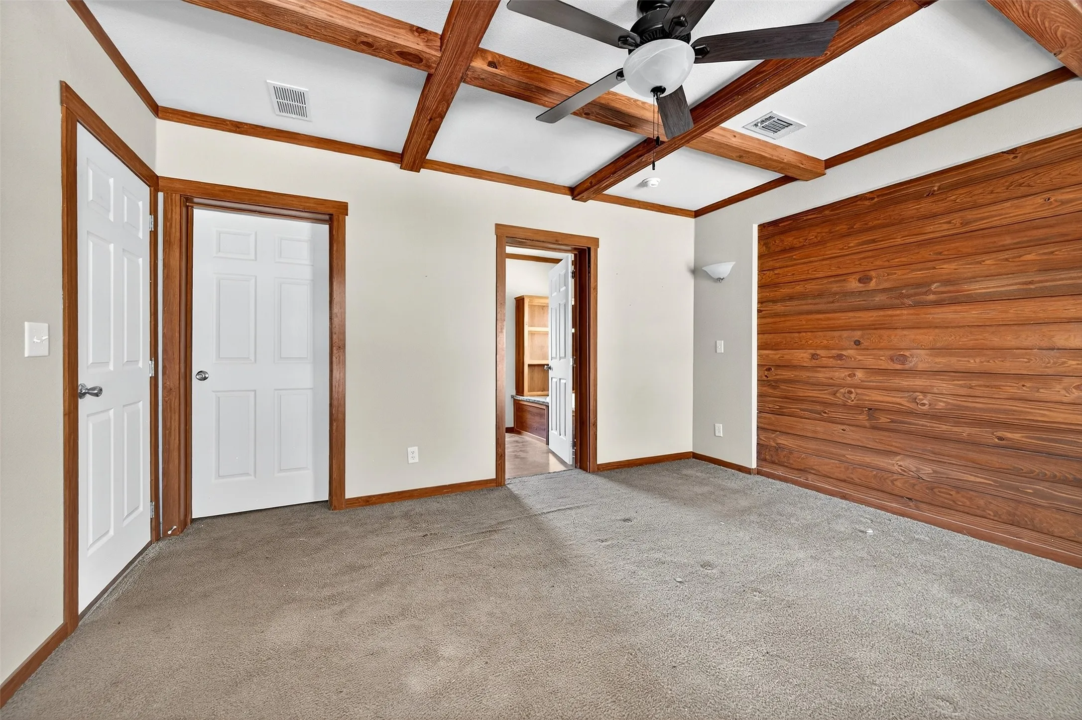 Unfurnished bedroom with ceiling fan, carpet flooring, beamed ceiling, coffered ceiling, and ensuite bathroom