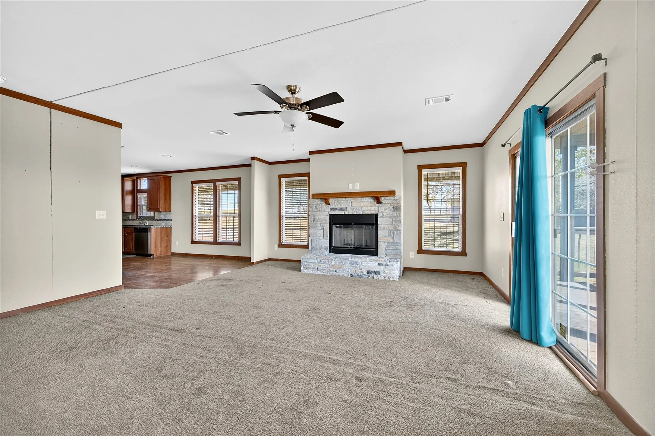 Unfurnished living room with a fireplace, ornamental molding, carpet flooring, and a ceiling fan