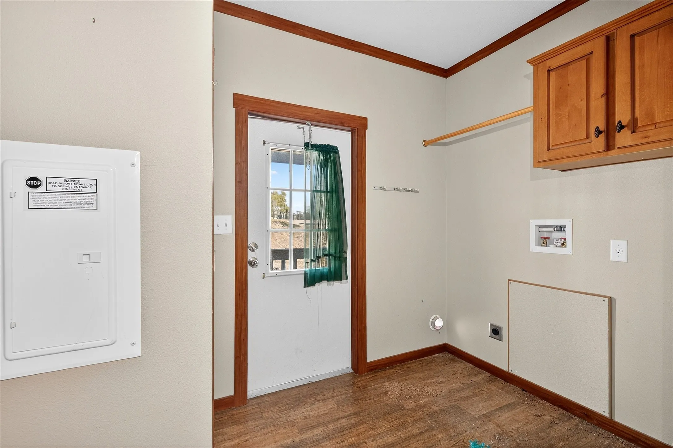 Washroom with electric panel, dark wood-type flooring, ornamental molding, electric dryer hookup, and washer hookup