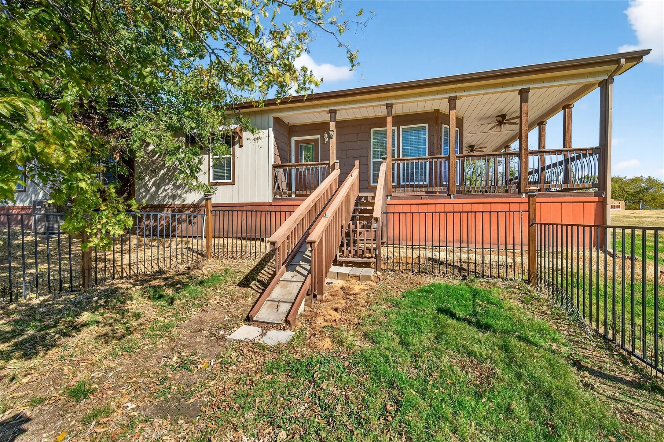 Back of property with a fenced backyard, a ceiling fan, covered porch, and stairs