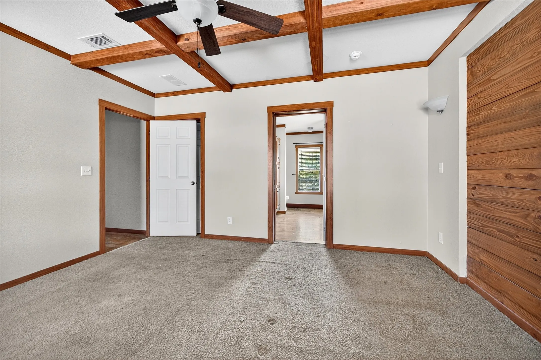 Unfurnished bedroom featuring beamed ceiling, carpet floors, a ceiling fan, and coffered ceiling