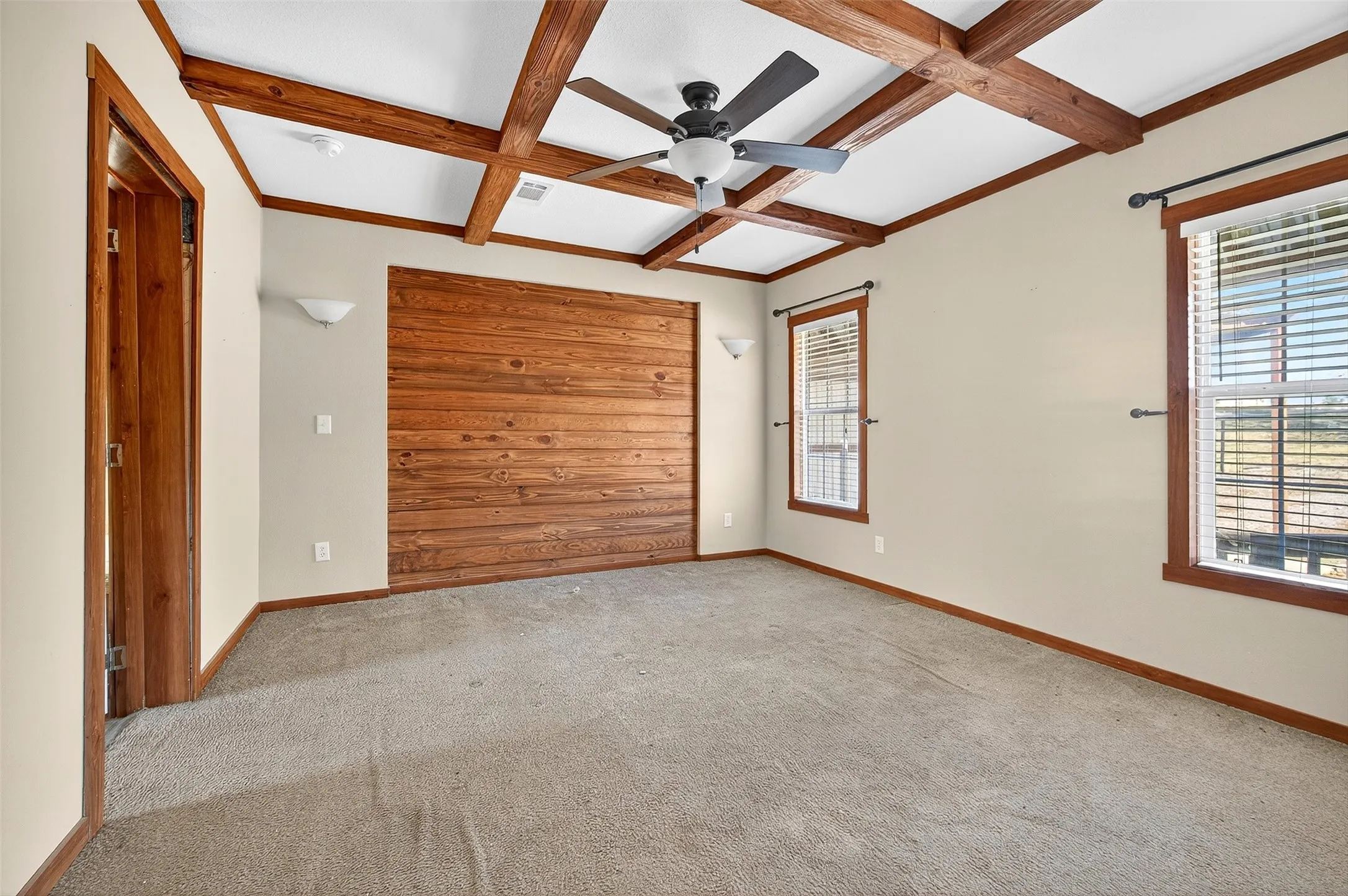 Carpeted empty room with coffered ceiling, beam ceiling, and ceiling fan