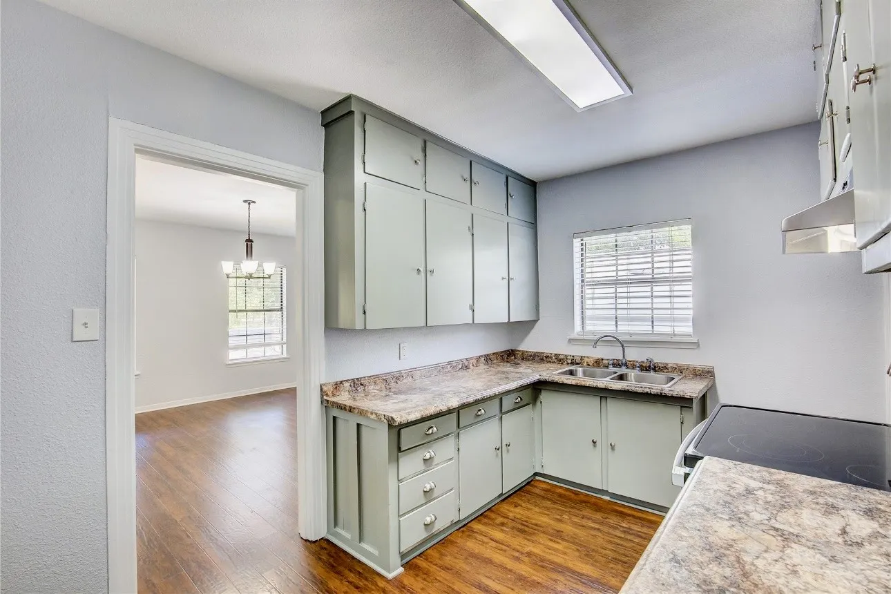 Kitchen with stove, an inviting chandelier, sink, dark hardwood / wood-style floors, and decorative light fixtures