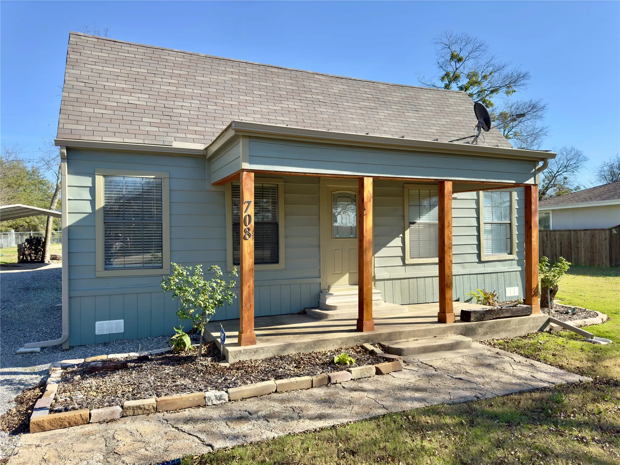 View of front of home with roof with shingles, a porch, and a detached carport