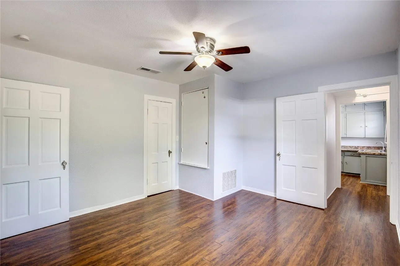 Unfurnished bedroom with baseboards, visible vents, and dark wood-style flooring