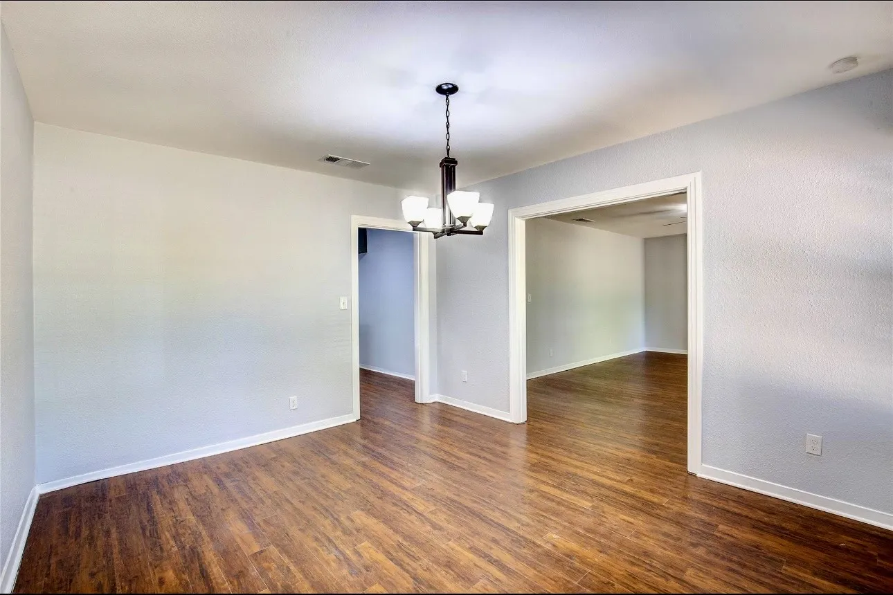 Unfurnished room with a chandelier and dark wood-type flooring
