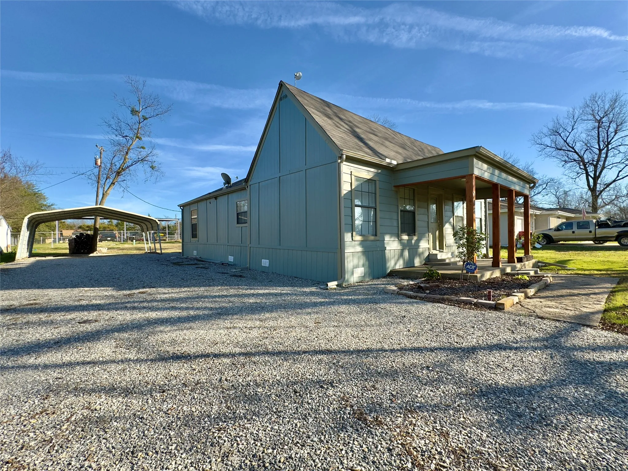 View of side of property with gravel driveway, a detached carport, a porch, and crawl space