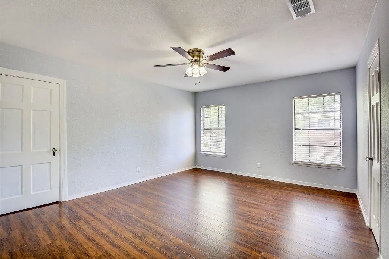 Empty room featuring ceiling fan and dark hardwood / wood-style flooring