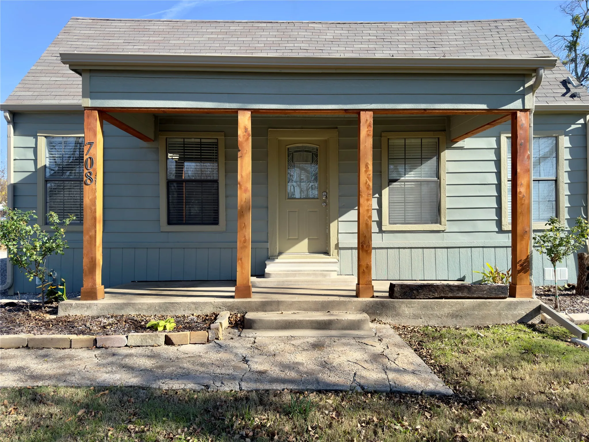 Doorway to property featuring a shingled roof and covered porch