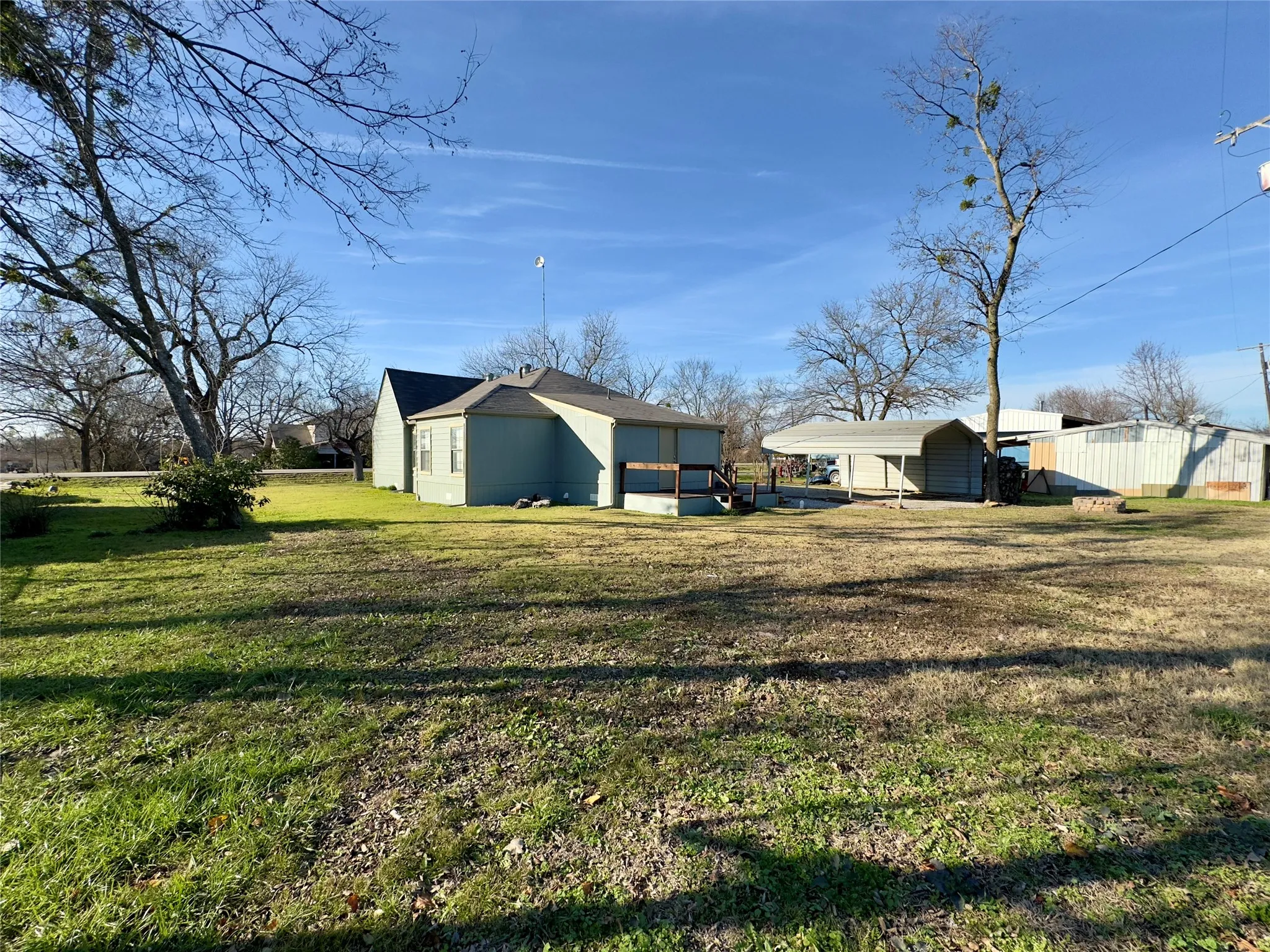 View of grassy yard with a detached carport
