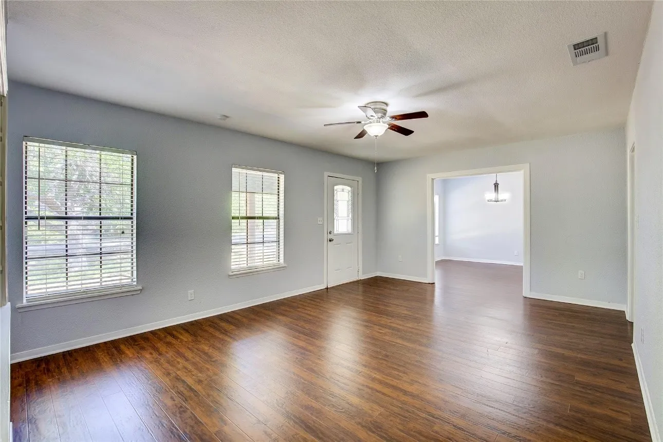 Unfurnished room with dark wood-type flooring and ceiling fan with notable chandelier