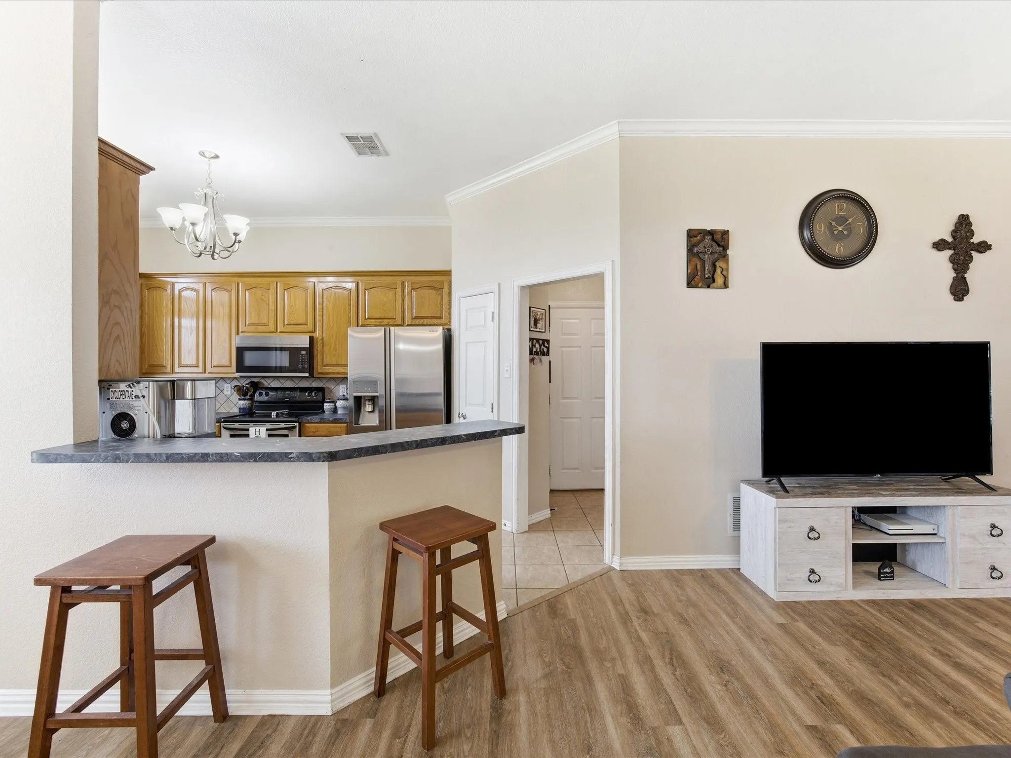 Kitchen featuring a kitchen bar, dark countertops, a peninsula, a chandelier, and stainless steel appliances