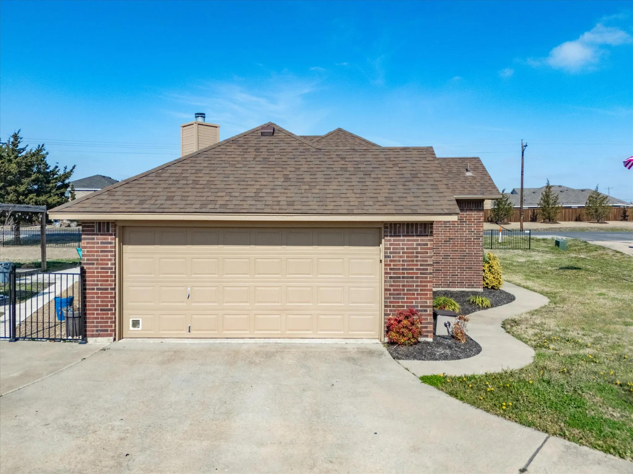 View of property exterior with brick siding, a shingled roof, and concrete driveway