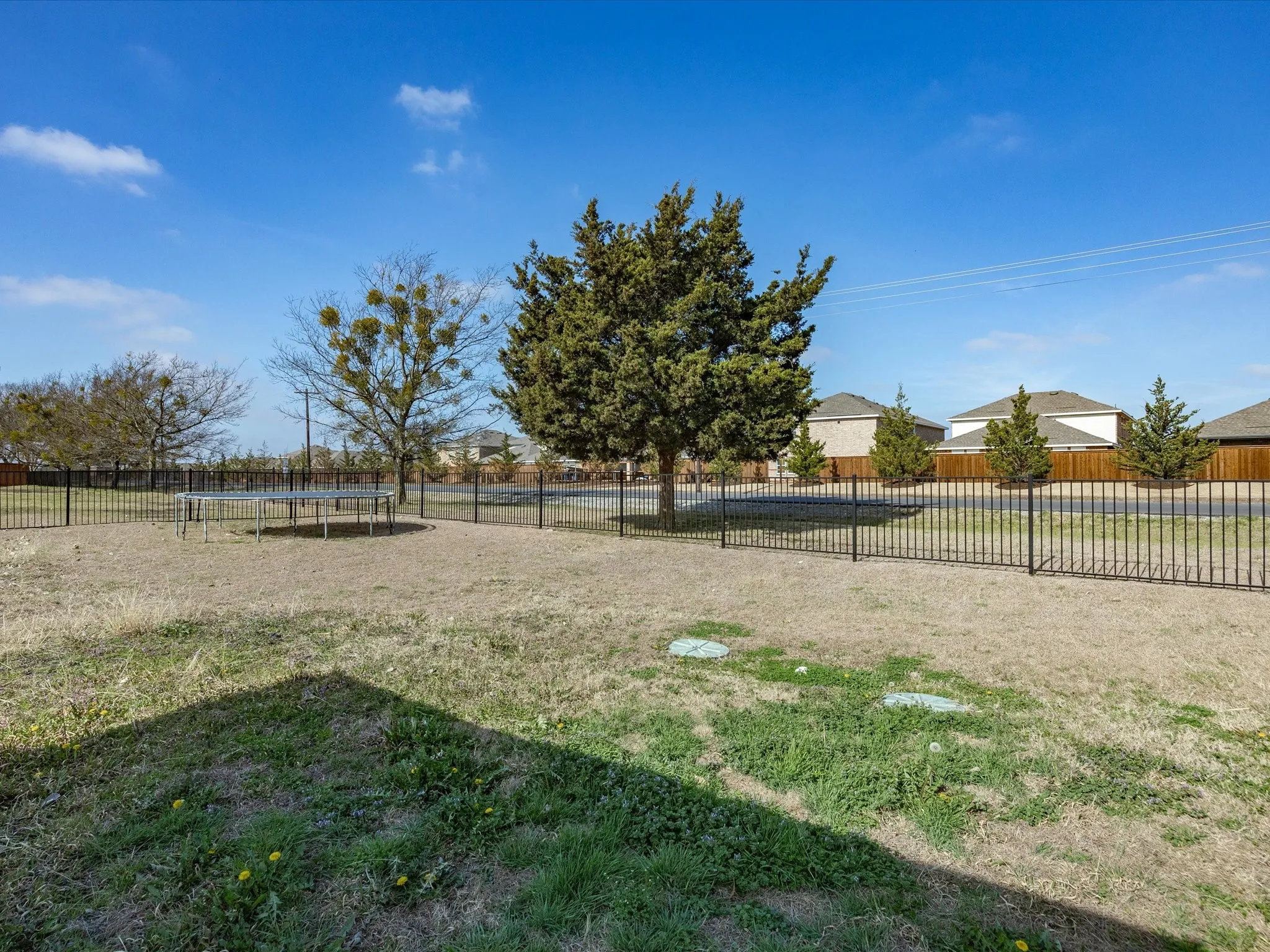 Fenced backyard featuring a trampoline