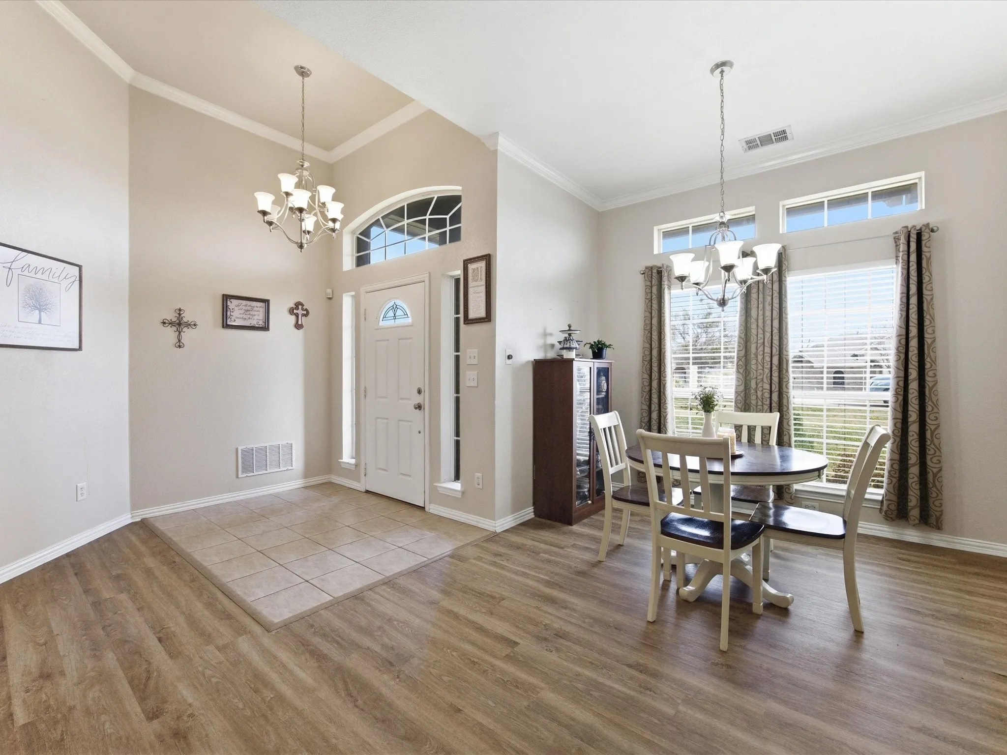 Foyer entrance featuring a chandelier, a high ceiling, ornamental molding, and light wood-type flooring