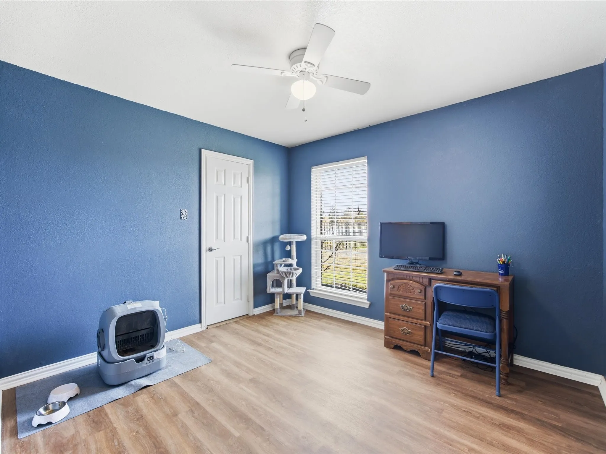 Office with light wood finished floors and a ceiling fan
