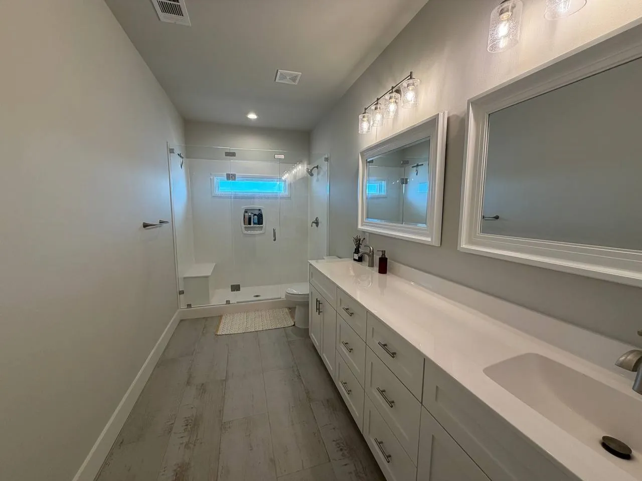 Bathroom featuring a shower stall, double vanity, light wood-style flooring, and recessed lighting