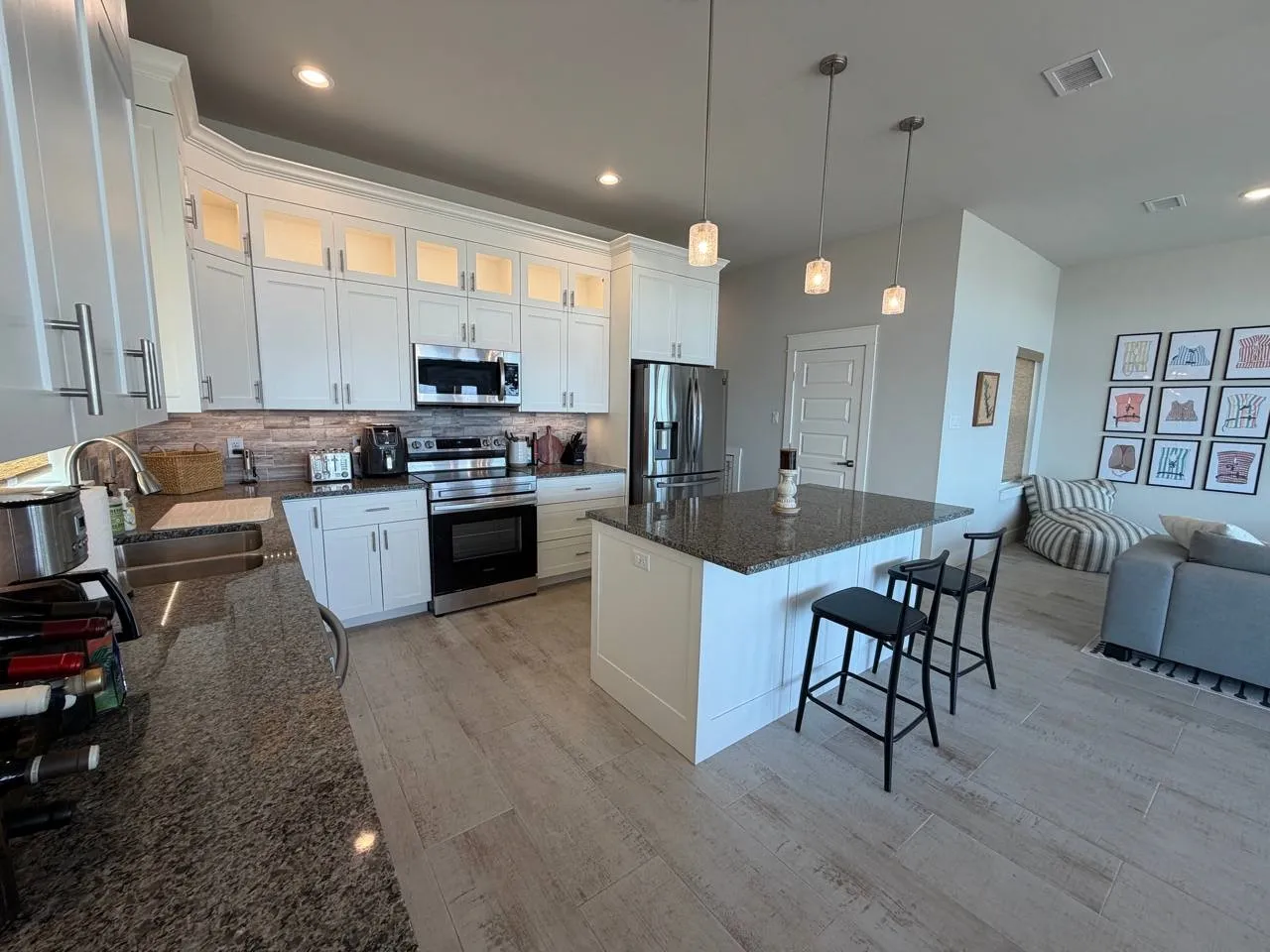 Kitchen featuring dark stone countertops, glass fronted cabinets, stainless steel appliances, a center island, and a kitchen bar