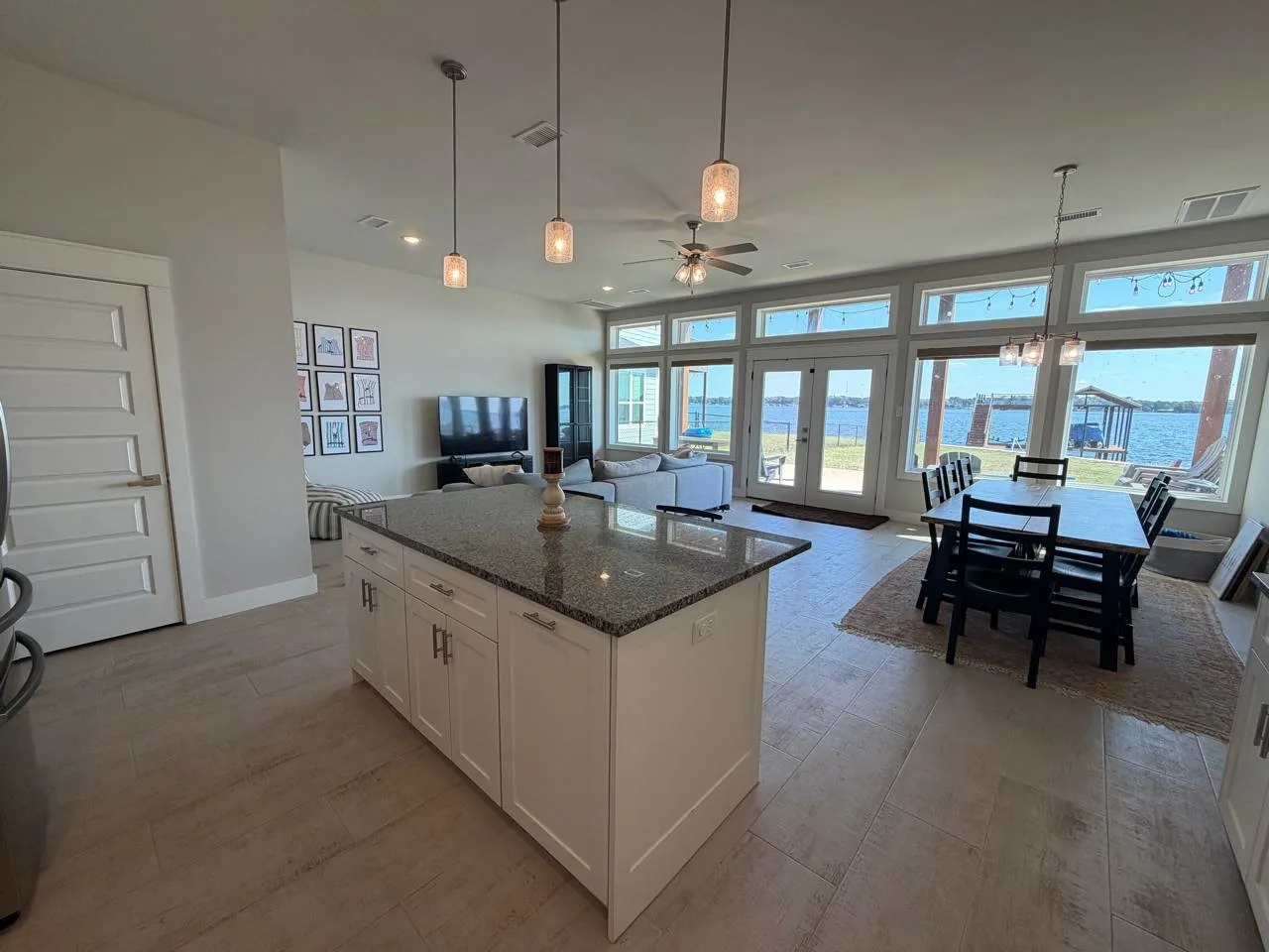 Kitchen featuring decorative light fixtures, white cabinets, dark stone countertops, open floor plan, and french doors