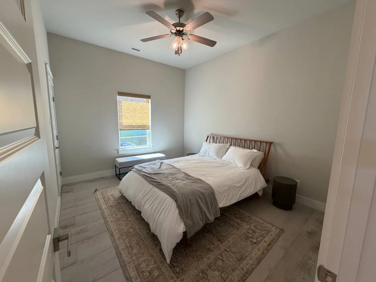 Downstairs bedroom with light tile floors and a ceiling fan