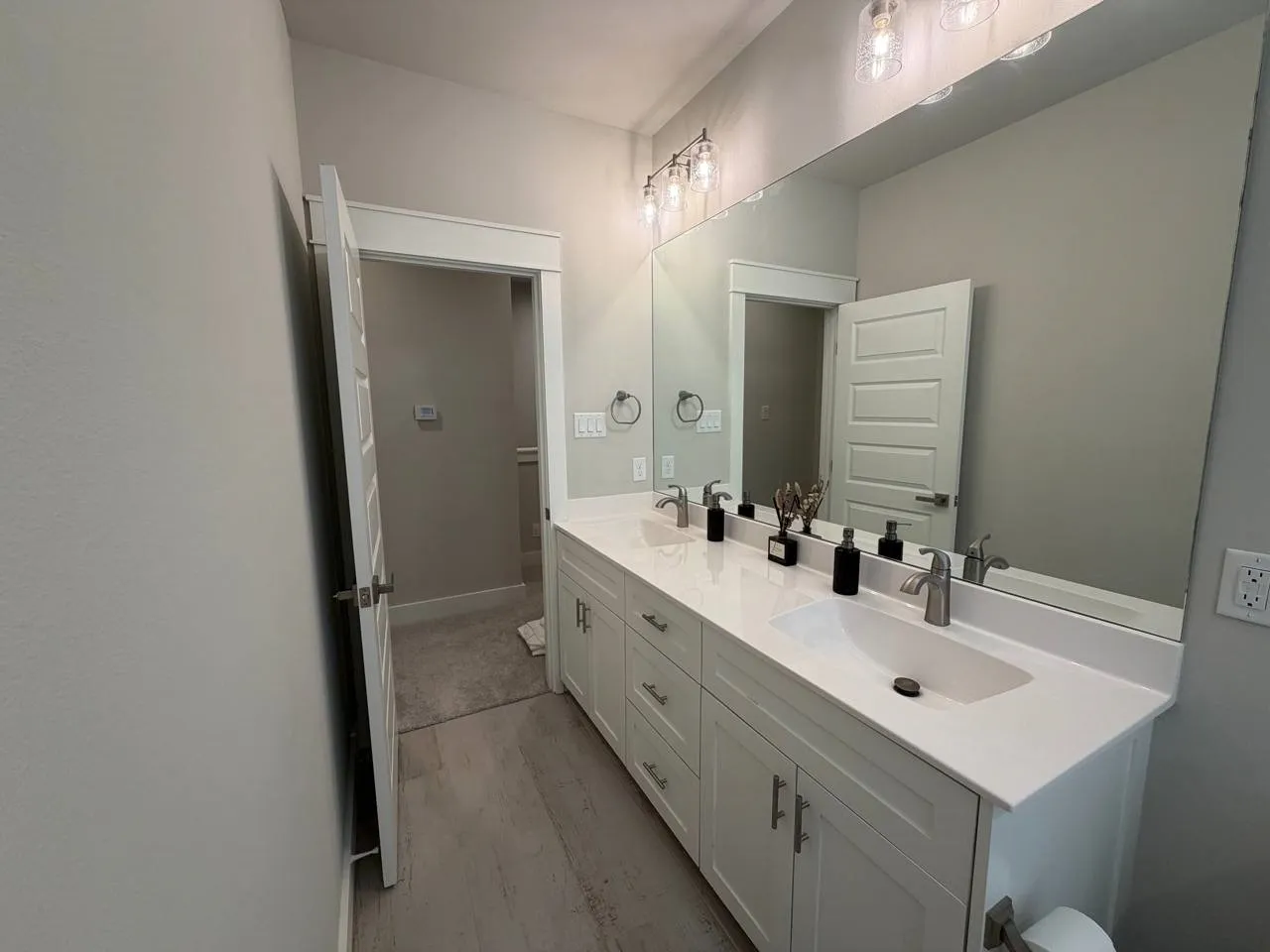 Full bath with double vanity and light wood-type flooring