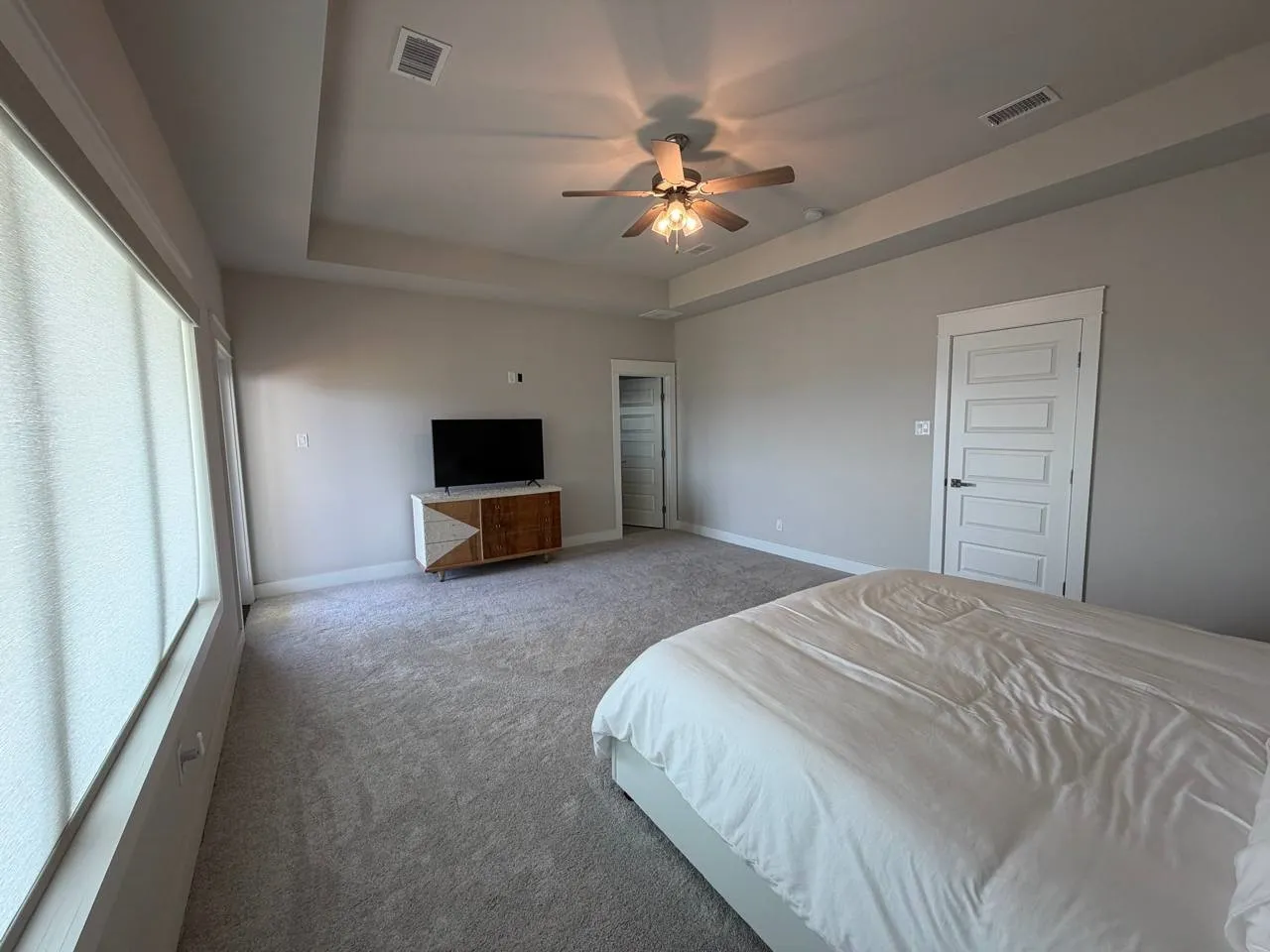 Bedroom featuring a ceiling fan, carpet flooring, and a raised ceiling