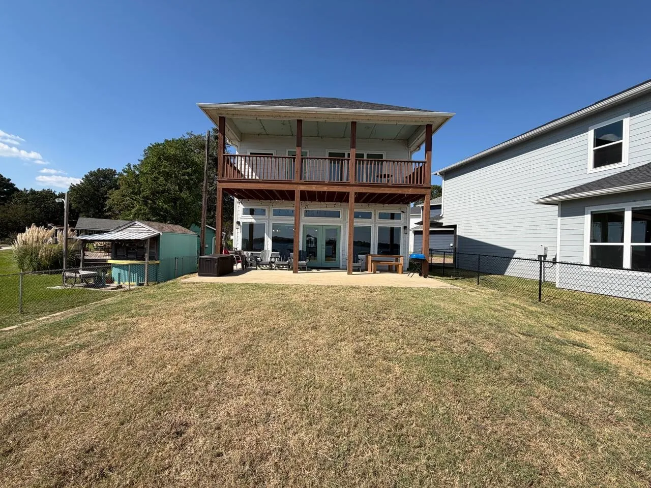 Rear view of property featuring a fenced backyard, a patio, french doors, and an outbuilding