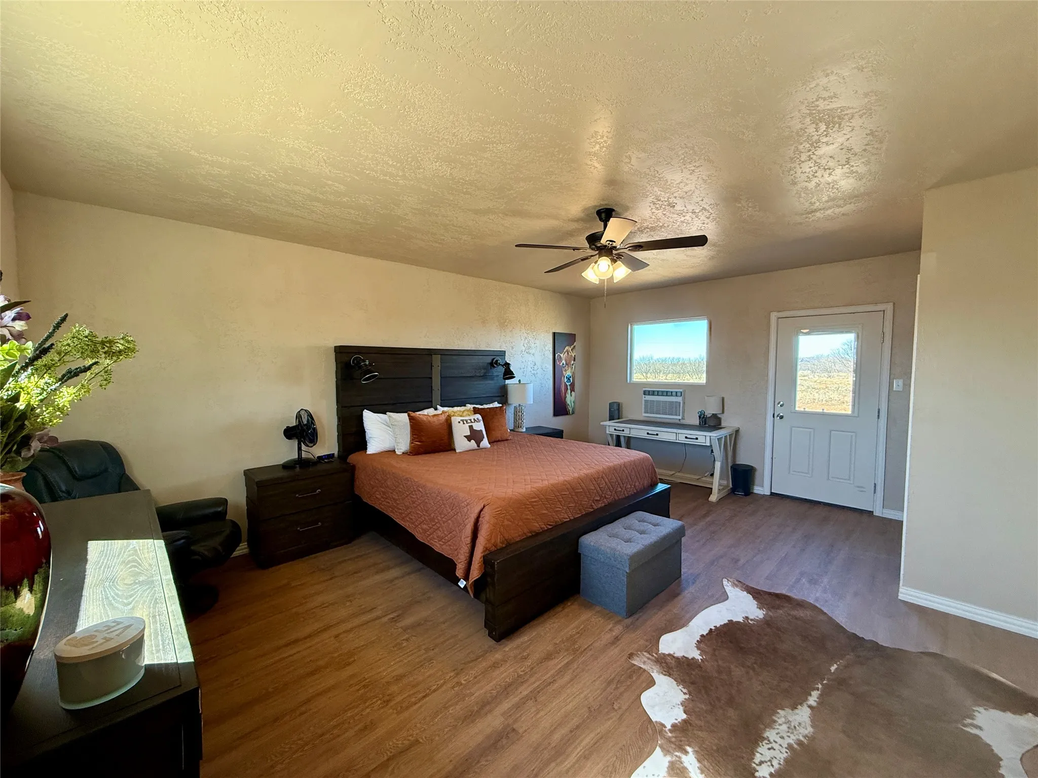 Bedroom featuring a textured ceiling, wood finished floors, a ceiling fan, and a textured wall