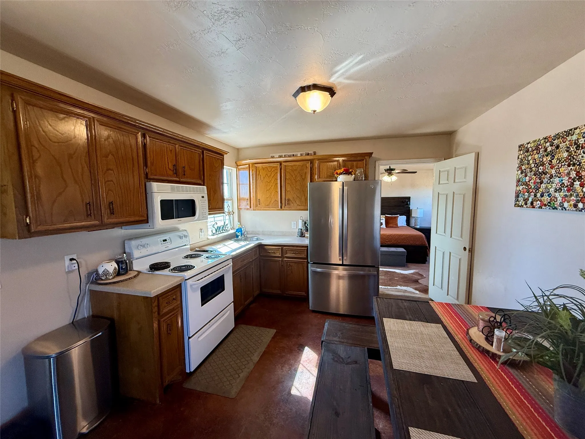 Kitchen with white appliances, light countertops, and wood finish cabinets