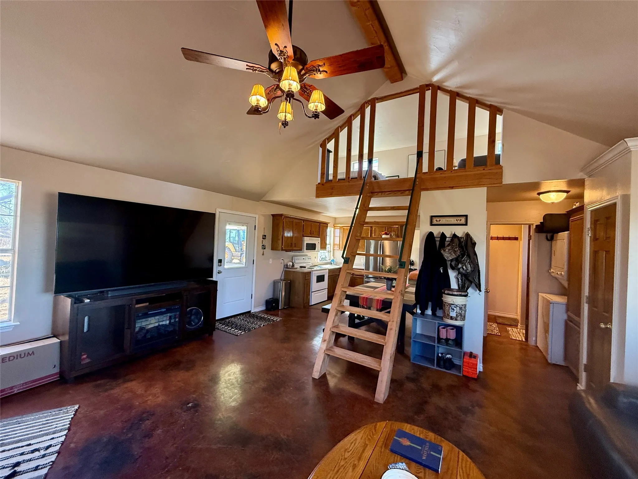 Living room with ceiling fan, finished concrete flooring, and lofted ceiling
