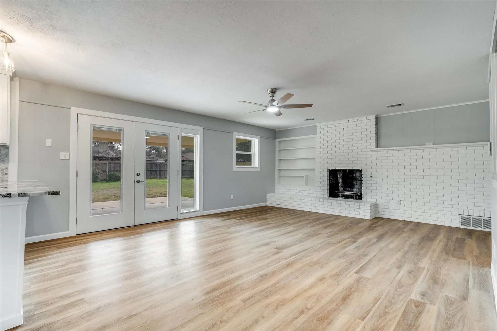 Spacious living room with French doors and wood burning fireplace.